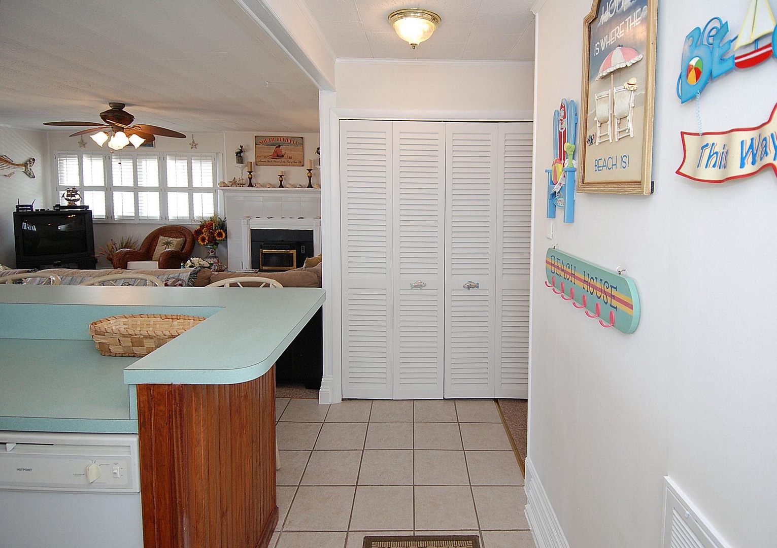 Bright, beach-themed kitchen with coastal decor, cozy living area, fireplace, and playful signs—perfect for making vacation meals and memories.