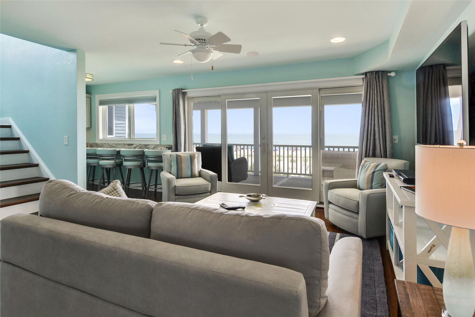 Sink into plush seating and soak in stunning ocean views through expansive glass doors. The open-concept layout invites you to relax, with coastal-cool tones wrapping you in tranquility.