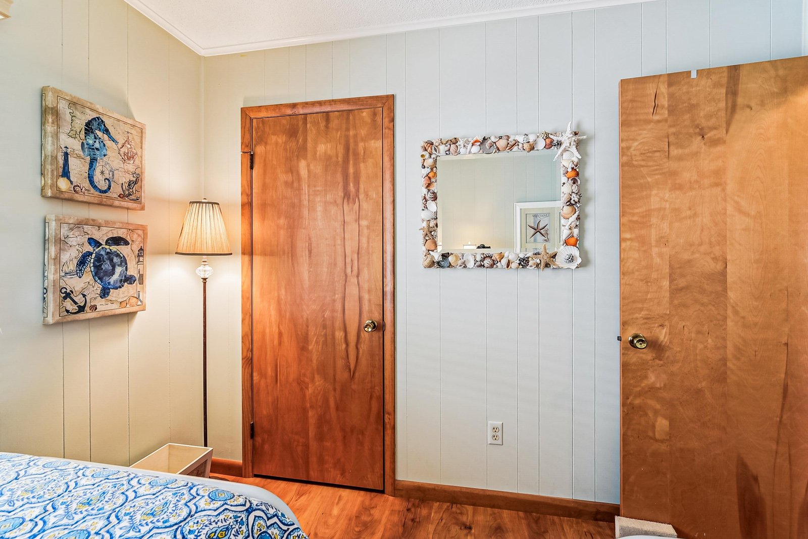 Step into your coastal-inspired bedroom with charming nautical touches, warm wood accents, and a seashell-adorned mirror that invites you to unwind in style.