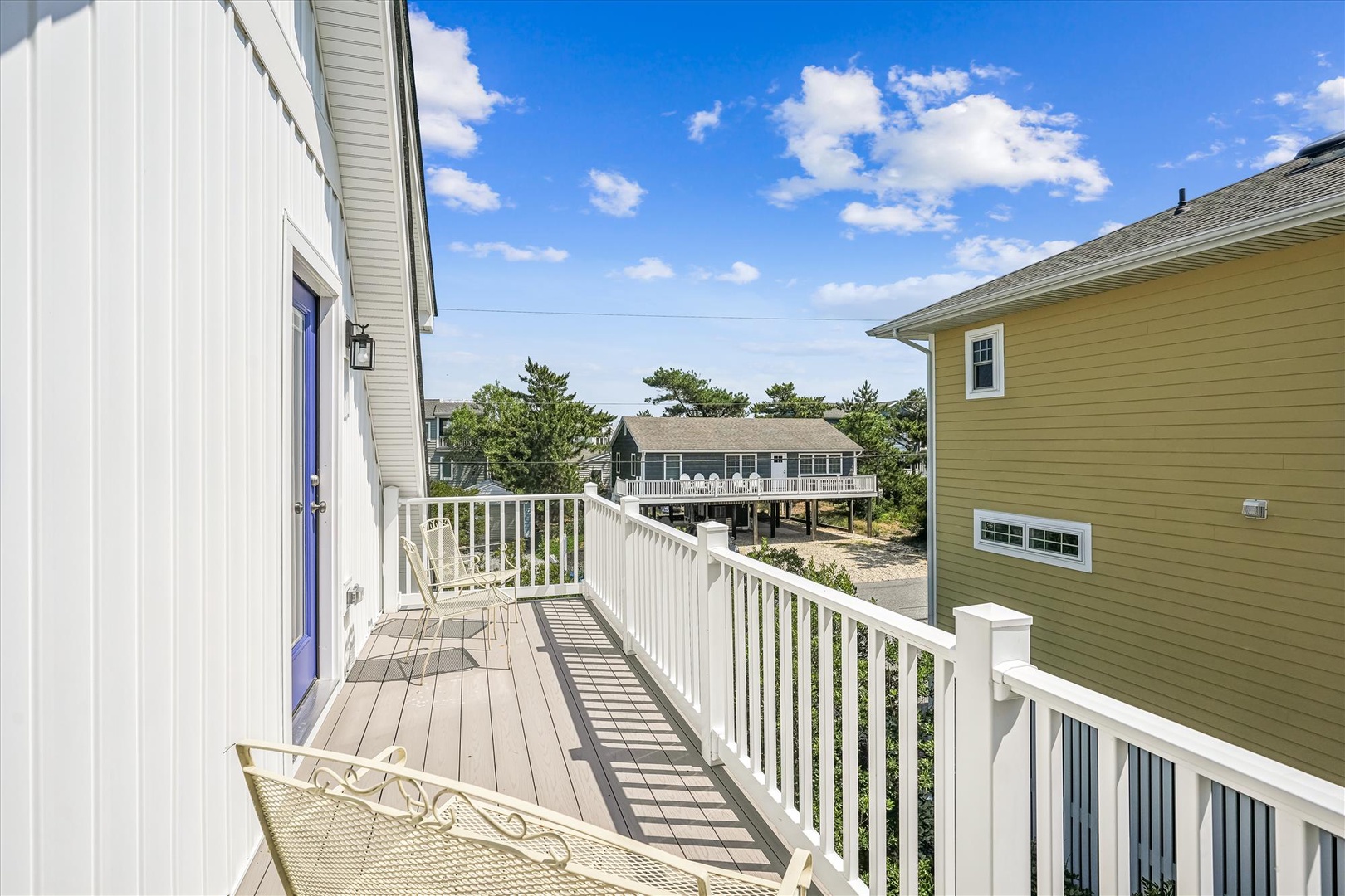Step out onto your private balcony and breathe in the coastal air. Sunny skies, neighboring beach homes, and tree-lined surroundings set a relaxed, vacation-ready mood.