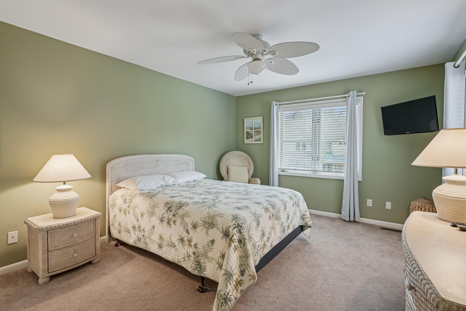 Step into your calming coastal retreat, where soft green tones and tropical-themed bedding create the perfect island escape. Enjoy restful nights under the gentle breeze of a ceiling fan, with modern TV entertainment at your fingertips.