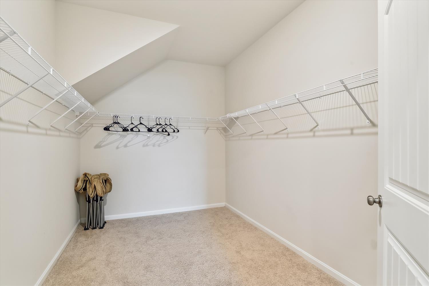 Spacious walk-in closet offers plenty of room for your belongings with wire shelving and carpet flooring.