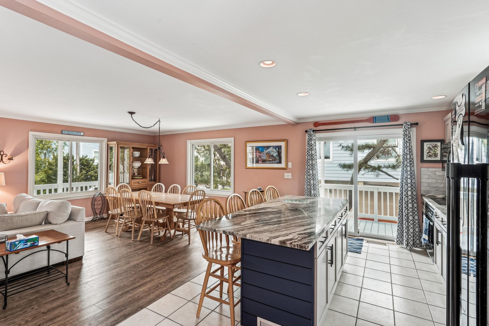 Sun-drenched open-concept space where kitchen, dining, and living flow seamlessly. Natural light streams through large windows, perfect for gathering or relaxing while enjoying peaceful water views.