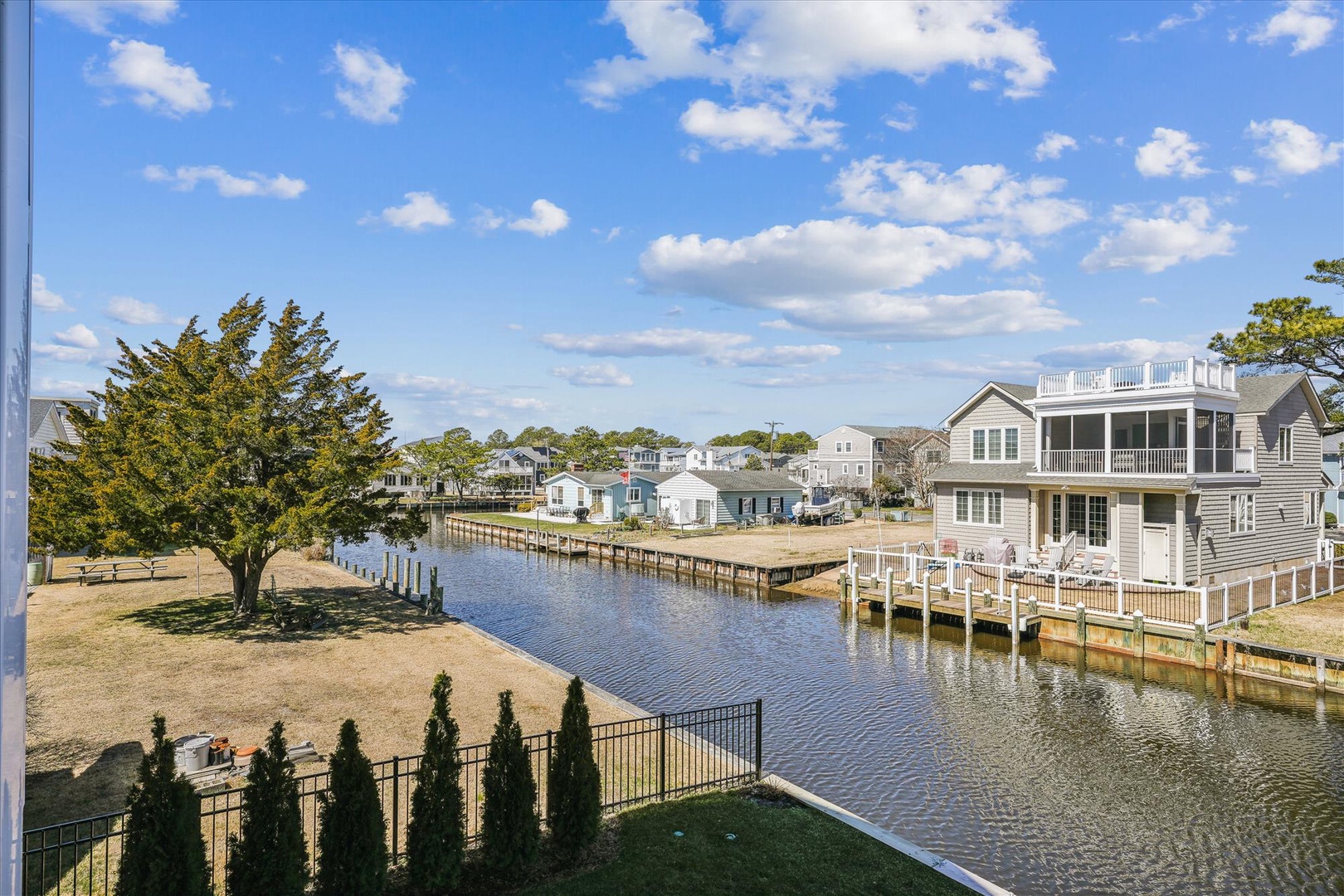 Waterfront community with canal views, wooden docks, and charming coastal homes under bright blue skies.