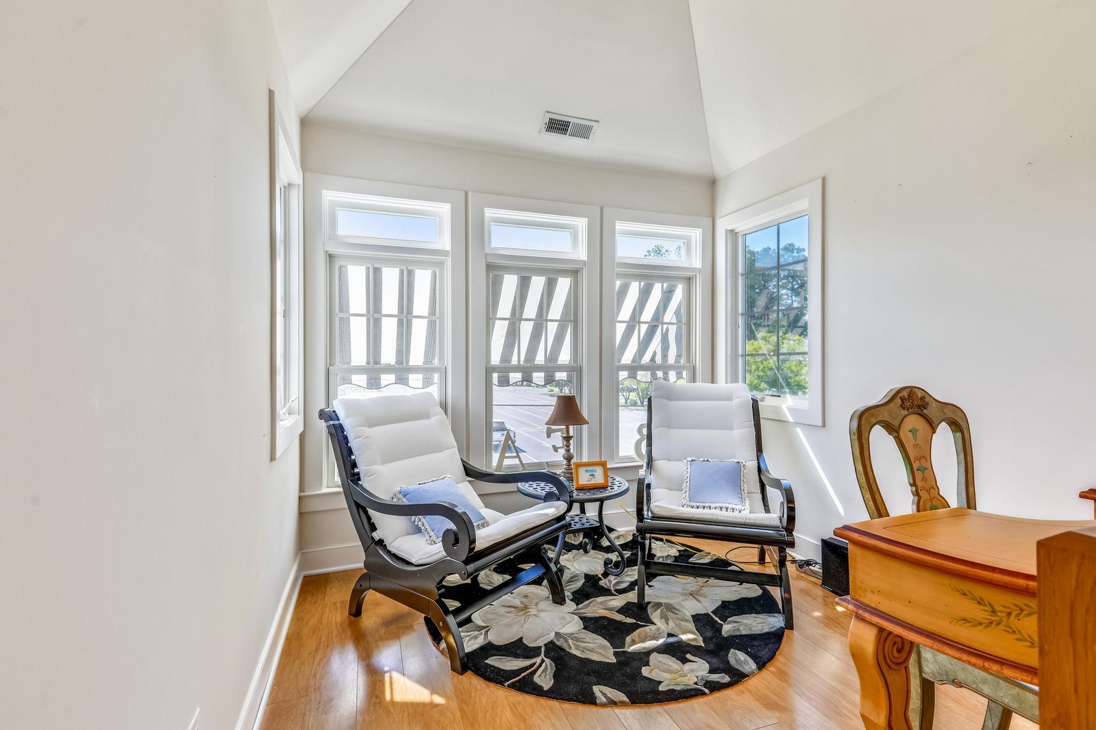 Settle into your own peaceful reading nook, where natural light floods through vaulted ceilings and elegant windows framing tranquil garden views. Perfect for morning coffee or quiet reflection.