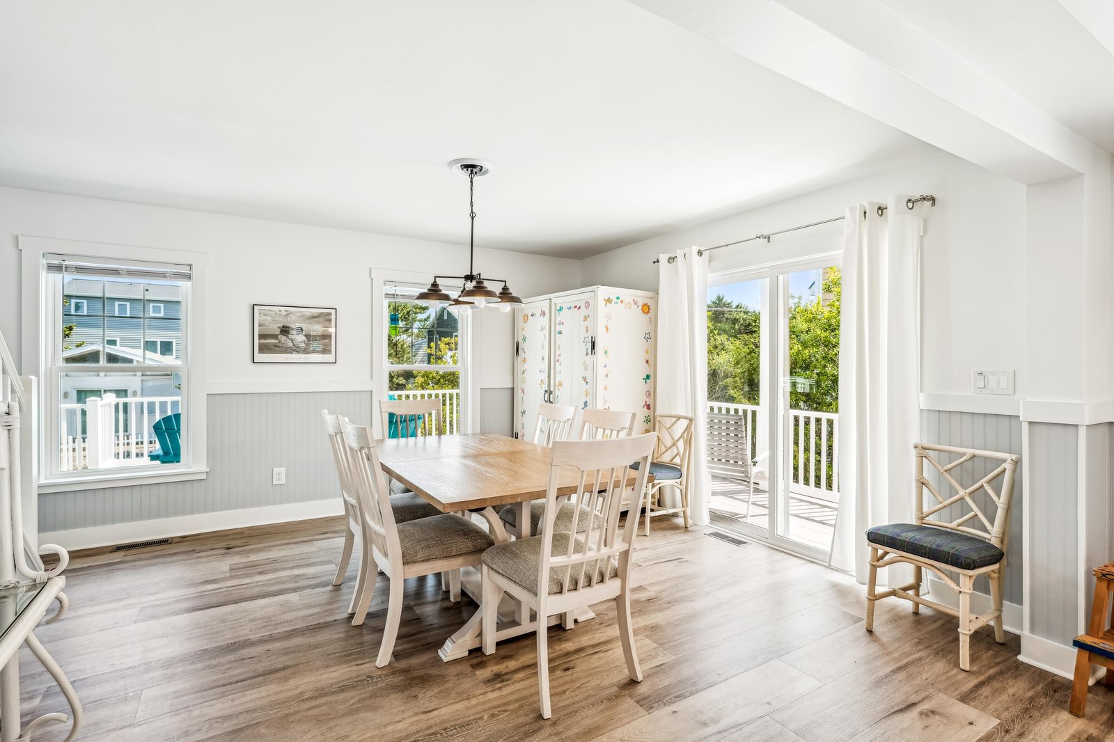 Gather around this inviting dining table where sunlight pours through French doors leading to your private deck. The airy space and coastal charm make every meal feel special.
