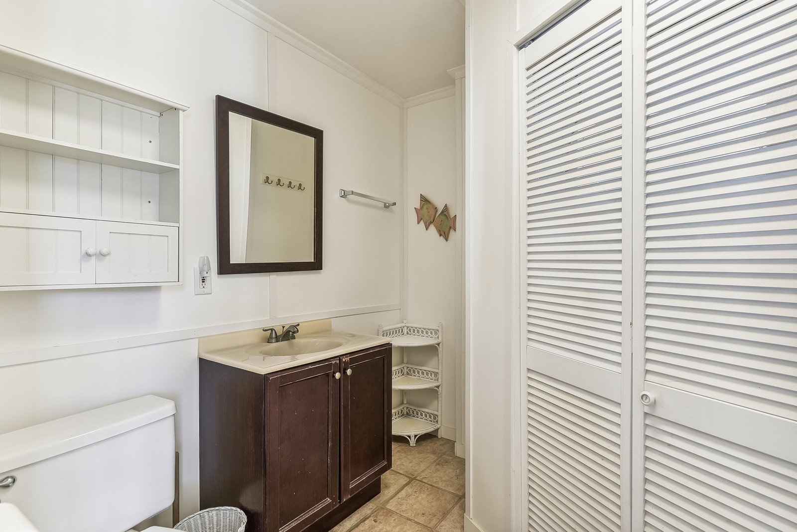 Step into this bright, refreshing bathroom with classic coastal charm. The dark wood vanity contrasts beautifully with crisp white shiplap, while open storage and handy built-in shelving keep your essentials close at hand.