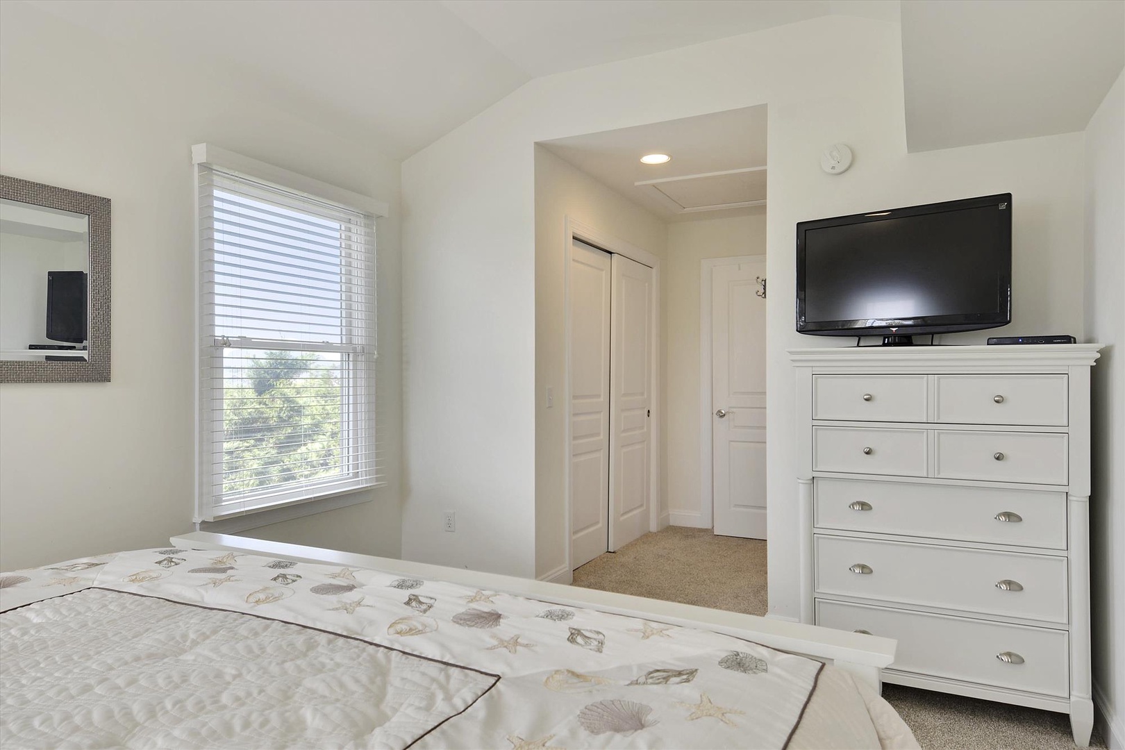 Your bright, airy bedroom with a comfortable queen bed, flat-screen TV, and dresser awaits—sunlight streaming through the window creates the perfect morning glow.