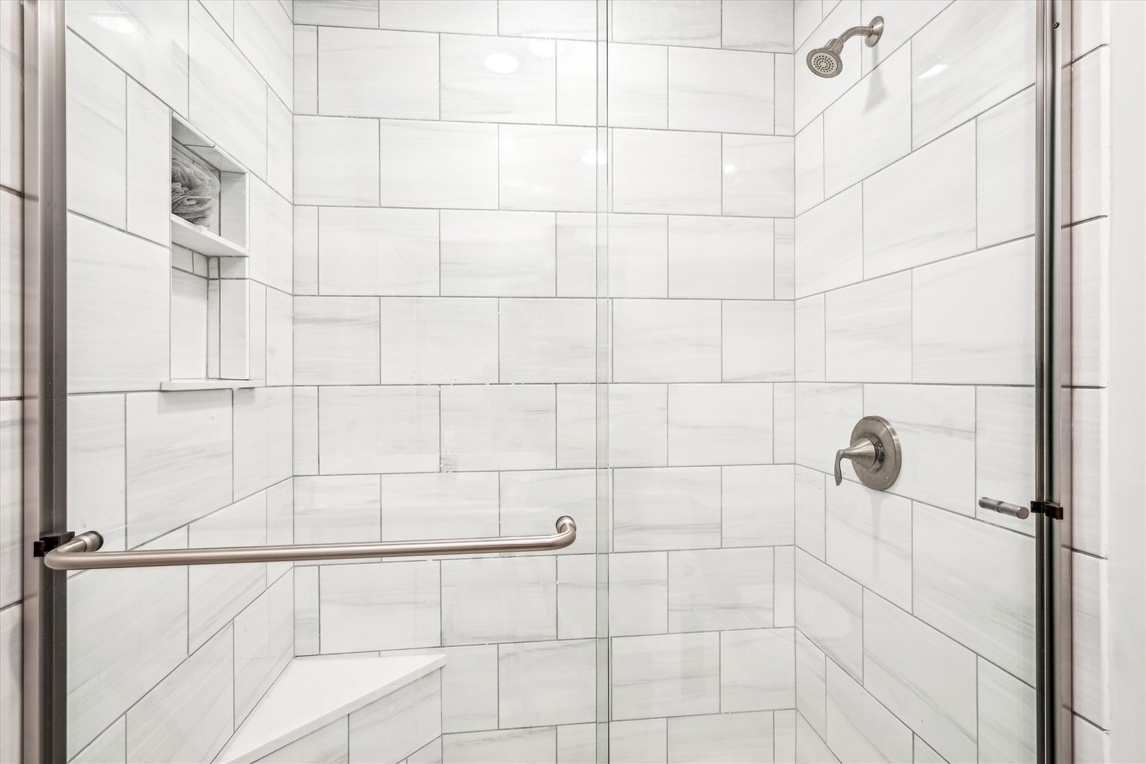 Step into your pristine marble shower with rainfall head and grab bars for comfort and safety during your refreshing daily ritual.