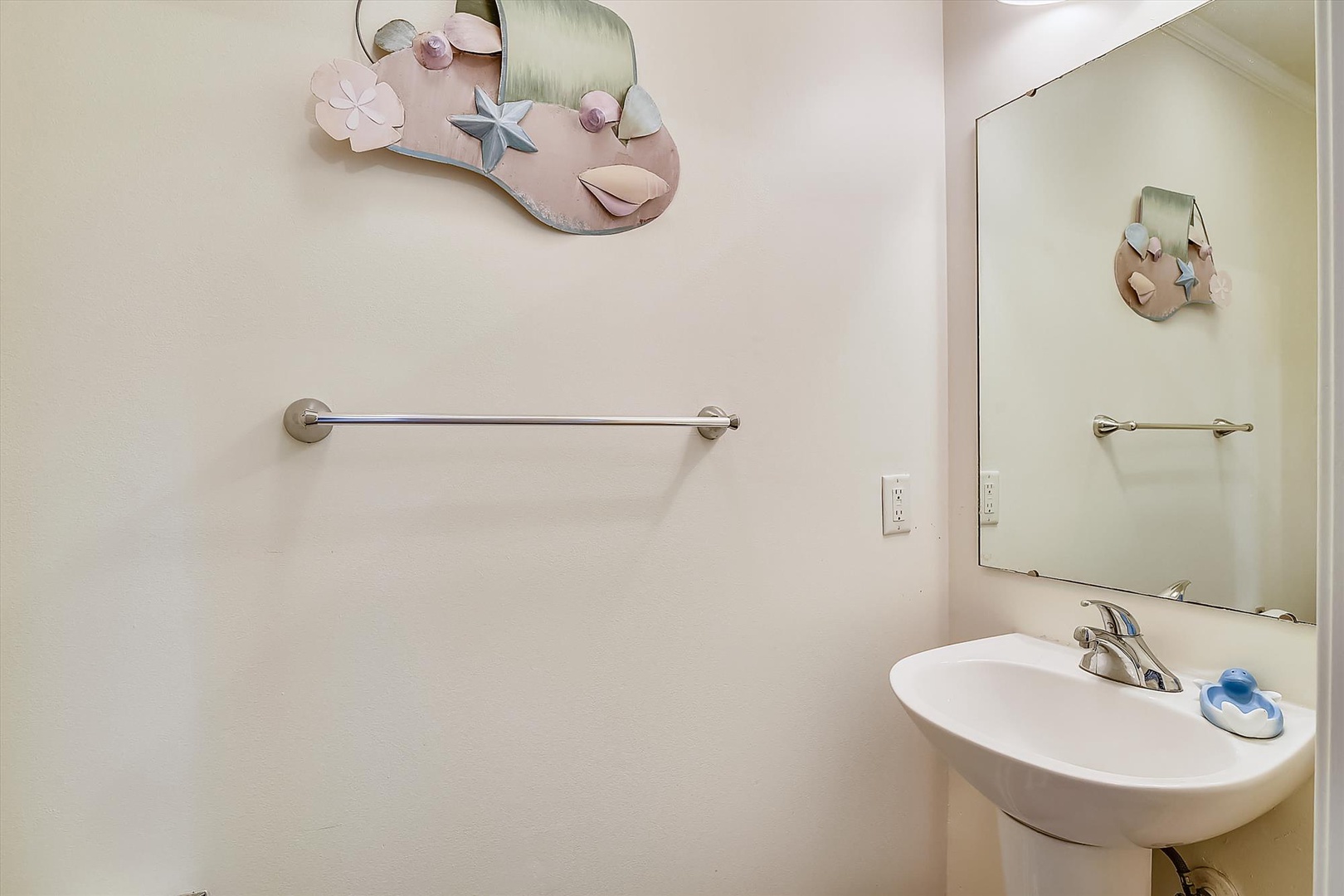 Your private bathroom features a clean sink, towel bar, and charming coastal decor to make freshening up feel like a seaside escape.
