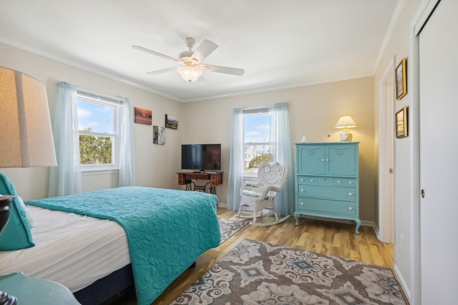 Sink into the plush bed and let the ceiling fan keep you cool as you unwind. Bright windows frame peaceful views, while thoughtful touches of teal add a cheerful, coastal charm to your personal retreat.