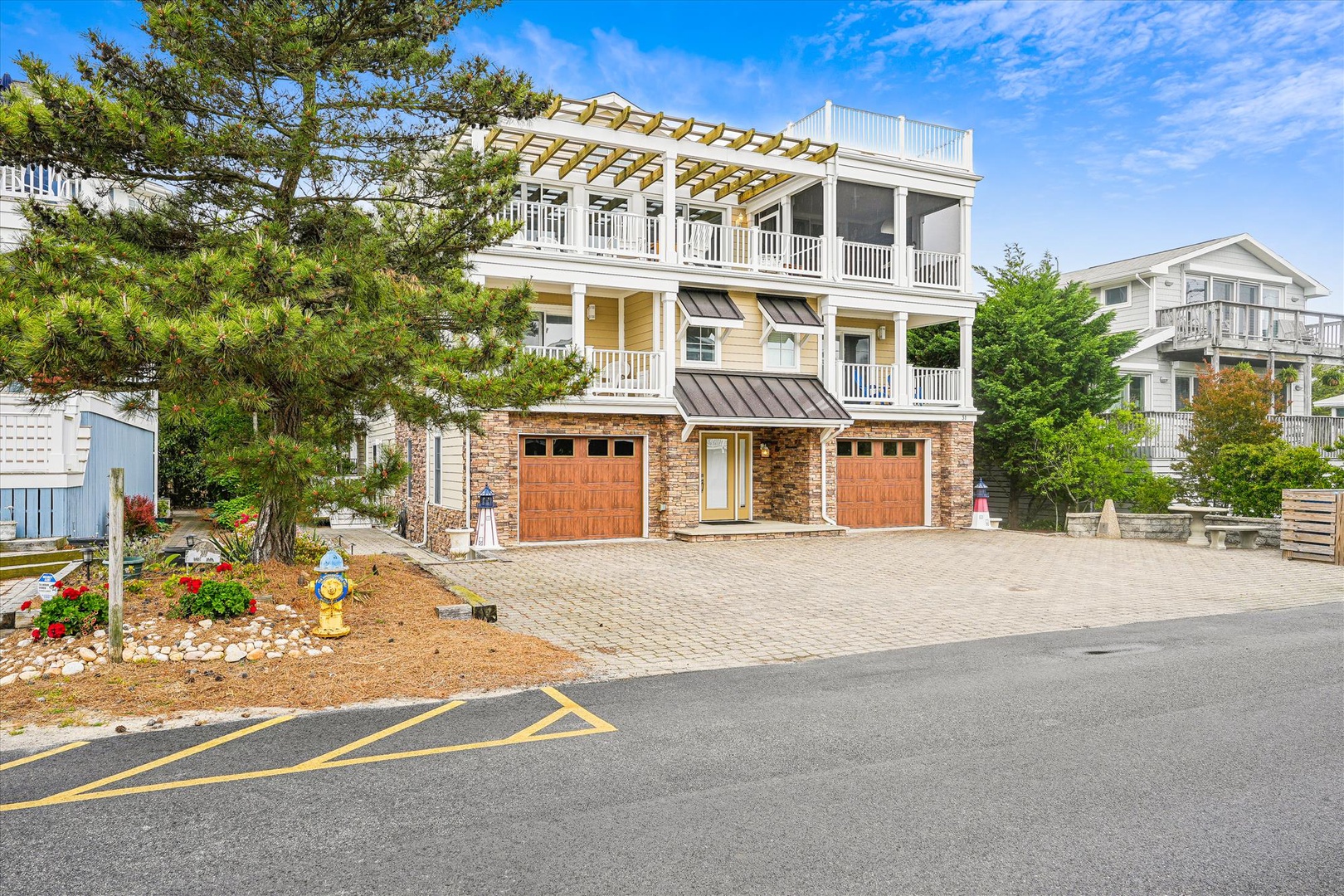 A coastal retreat nestled in a quiet neighborhood, featuring elegant white railings, dual garages, and a rooftop deck perfect for soaking in ocean breezes and stunning views.