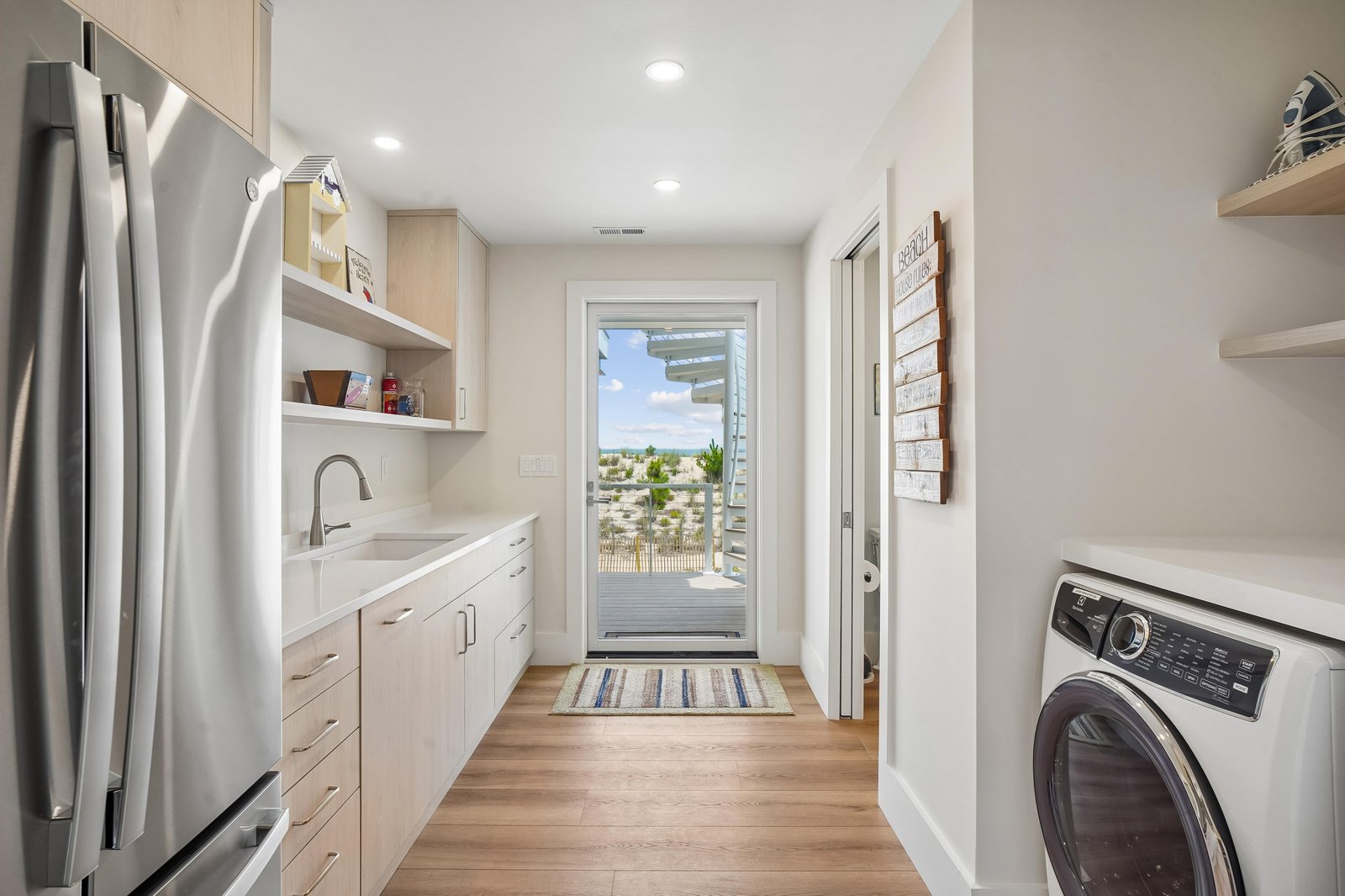 Bright and organized laundry space with modern appliances, ample storage, and views of the surrounding area through the doorway.
