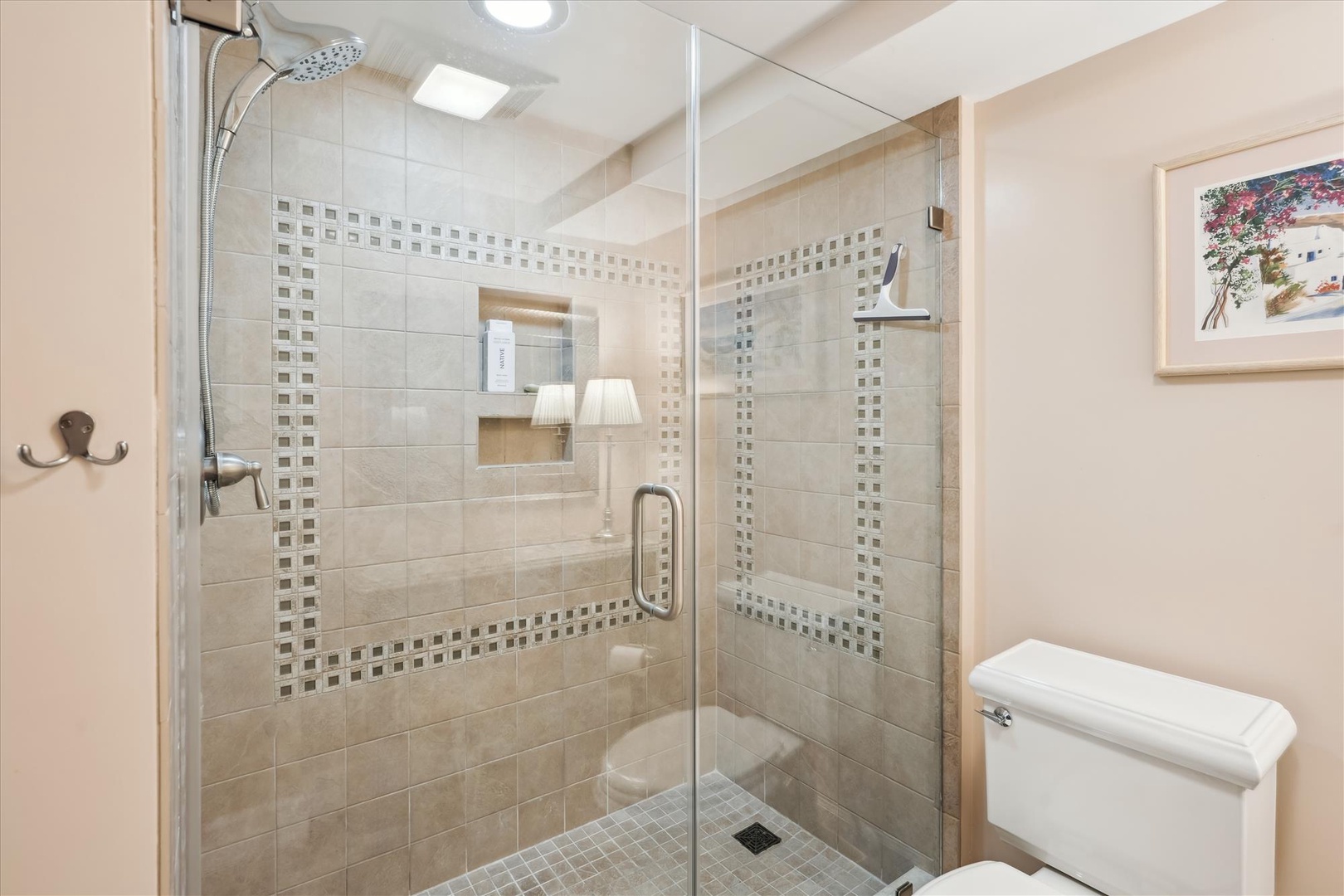 Step into your private spa-like bathroom featuring a spacious walk-in shower with elegant mosaic tile accents and rainfall showerhead for pure relaxation.
