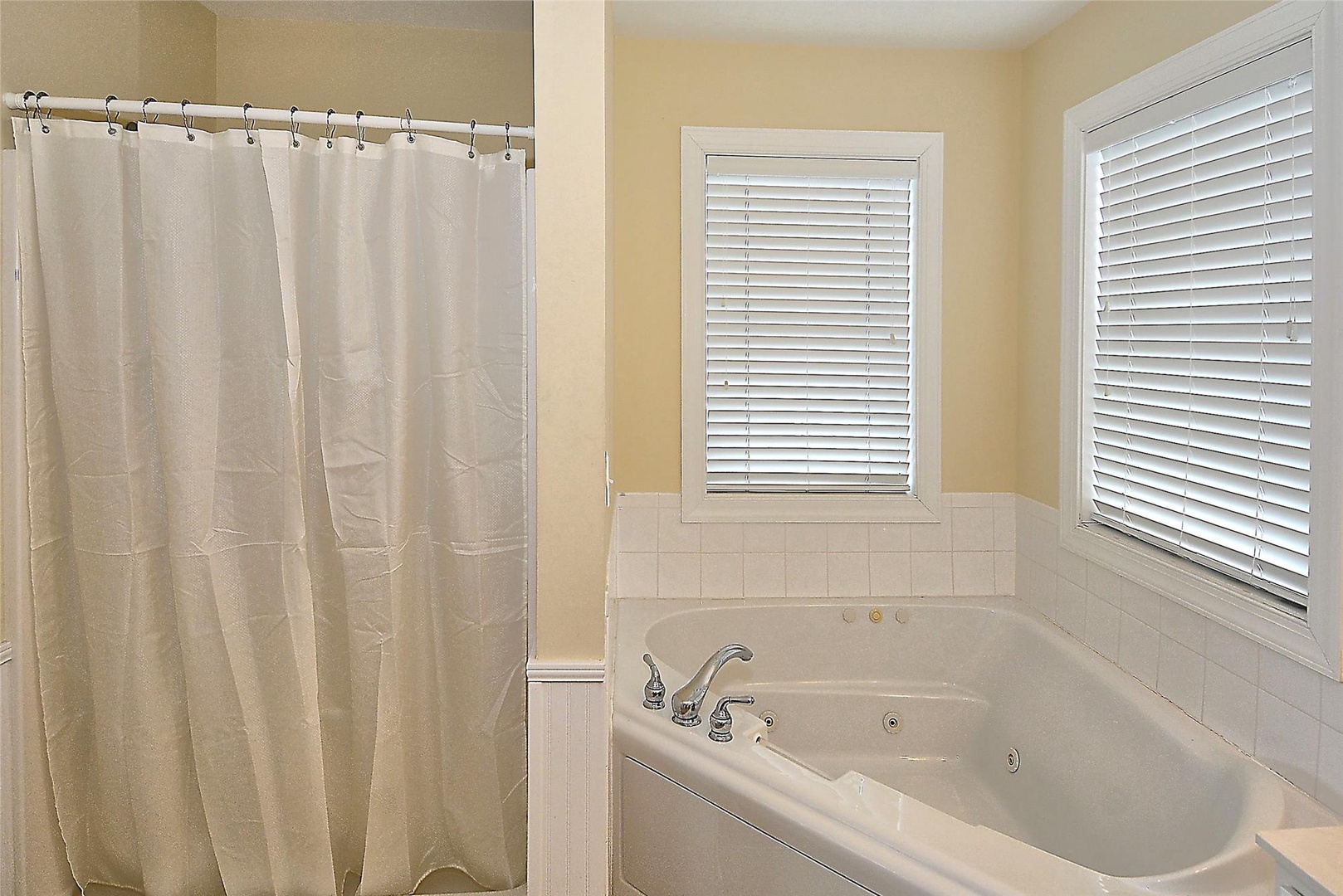 Unwind in your private bathroom featuring a soothing jetted tub and separate shower, with soft natural light from dual windows creating a peaceful retreat after your day's adventures.