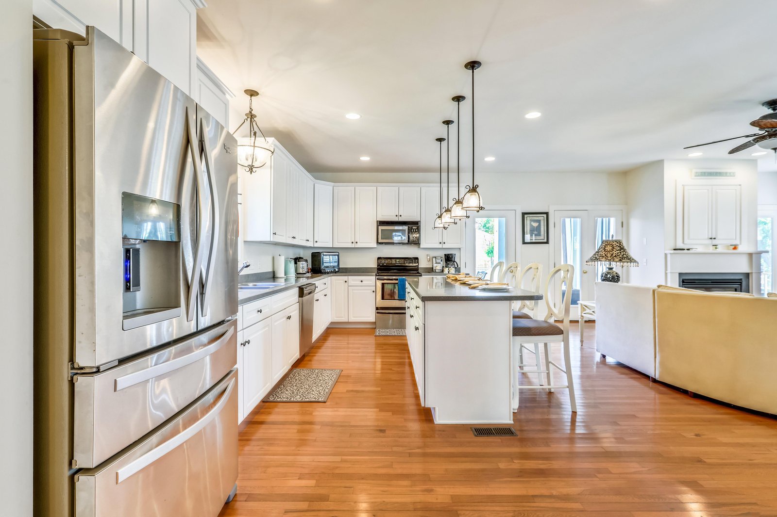 Your chef-ready kitchen glows with natural light and welcoming warmth, featuring sleek stainless appliances, ample counter space, and an inviting island perfect for morning coffee or meal prep.