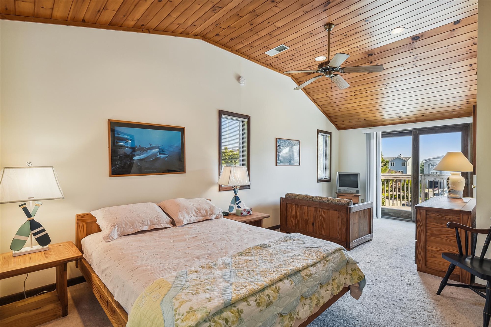 Unwind in your charming bedroom with a vaulted wood ceiling, cozy bed, and balcony access offering peaceful neighborhood views—your restful retreat awaits.
