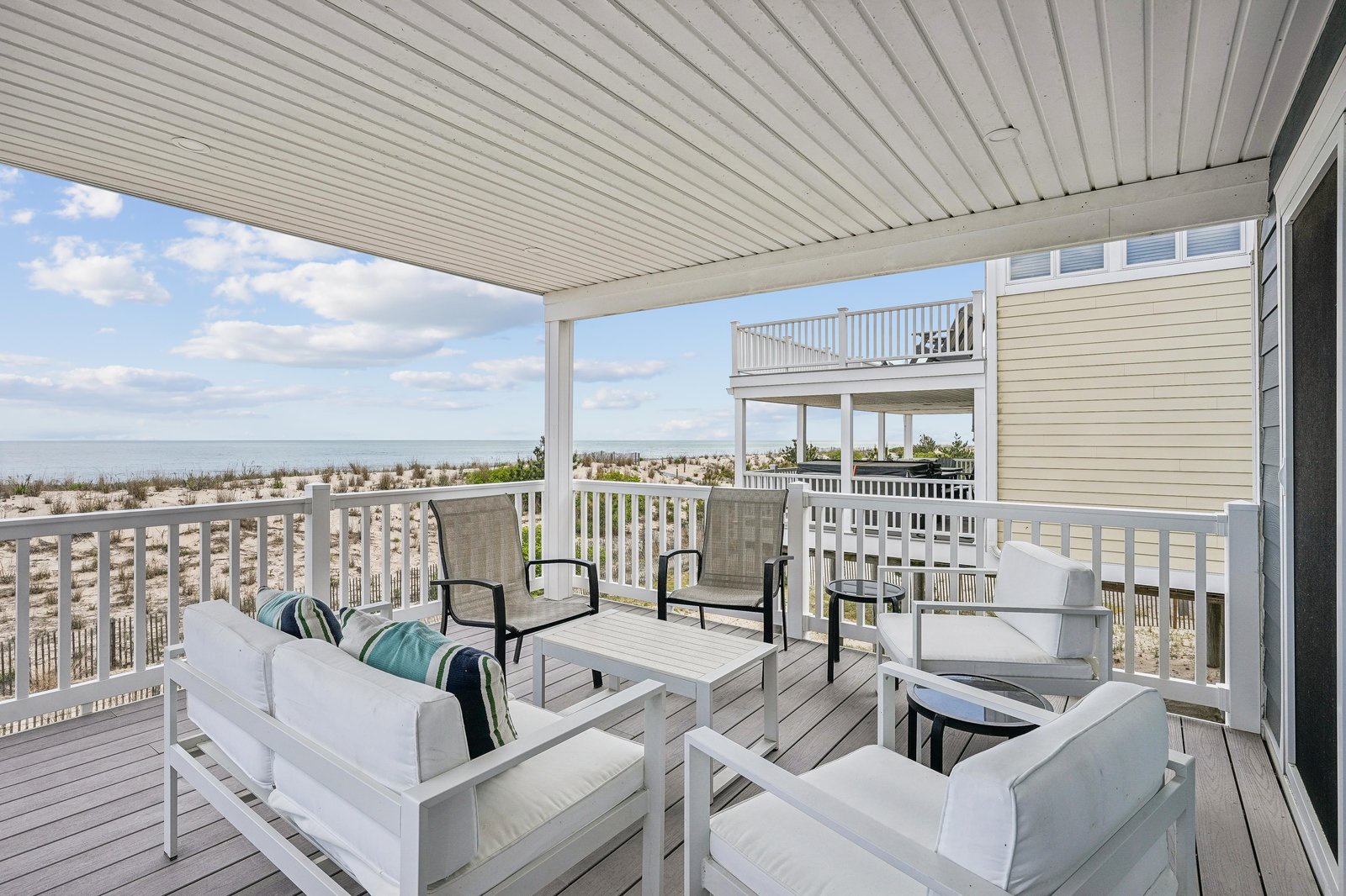 Step out onto your private deck and sink into plush seating as the ocean breeze surrounds you. This sheltered terrace frames stunning beach views, offering the perfect spot to sip morning coffee or watch the sun set over the dunes.