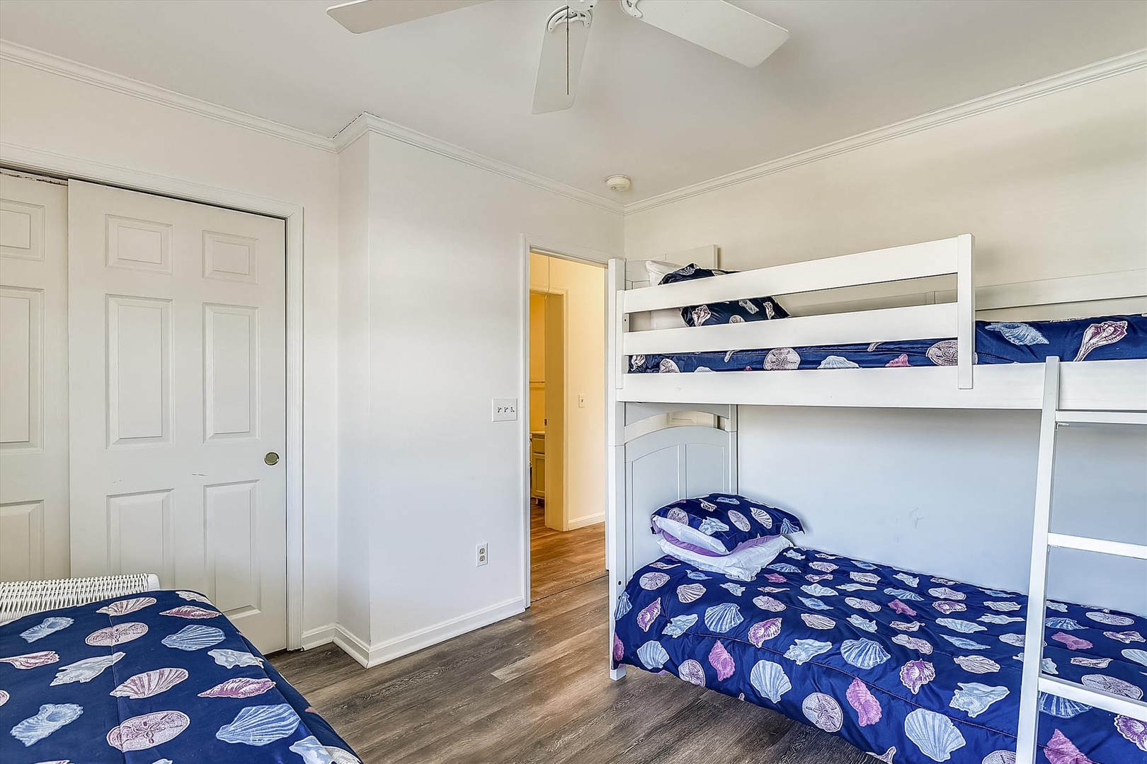 Sleep well in this bright room featuring a bunk bed and single bed, all dressed in cheerful seashell-themed bedding. Perfect for families or groups looking to share a cozy space together.