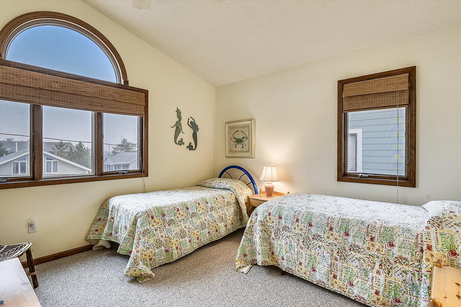 Two cozy twin beds draped in cheerful quilts welcome you into this airy coastal bedroom. Charming mermaid décor and warm wooden accents create a relaxed, beachy atmosphere perfect for unwinding after a day exploring the shore.