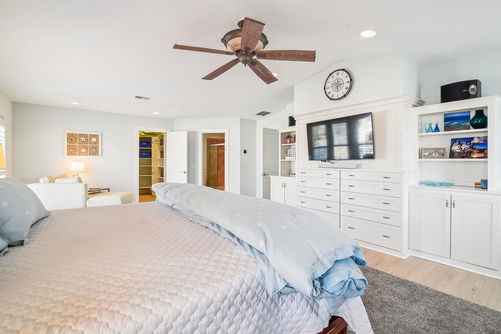 Relax in your spacious master suite with crisp white built-ins, a cozy seating nook, and coastal décor that invites restful nights and easy mornings.