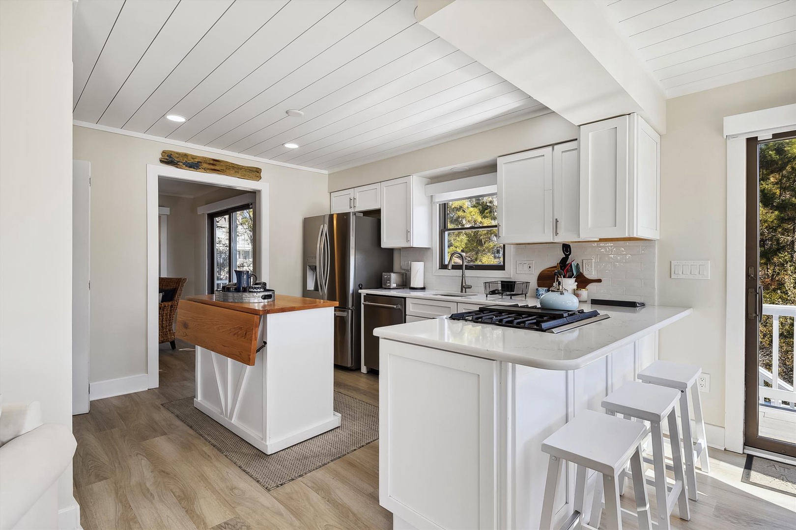 Your bright, modern kitchen features stainless steel appliances, a gas cooktop, and cozy breakfast bar seating—perfect for preparing meals and enjoying leisurely mornings with coffee while sunlight streams through the windows.