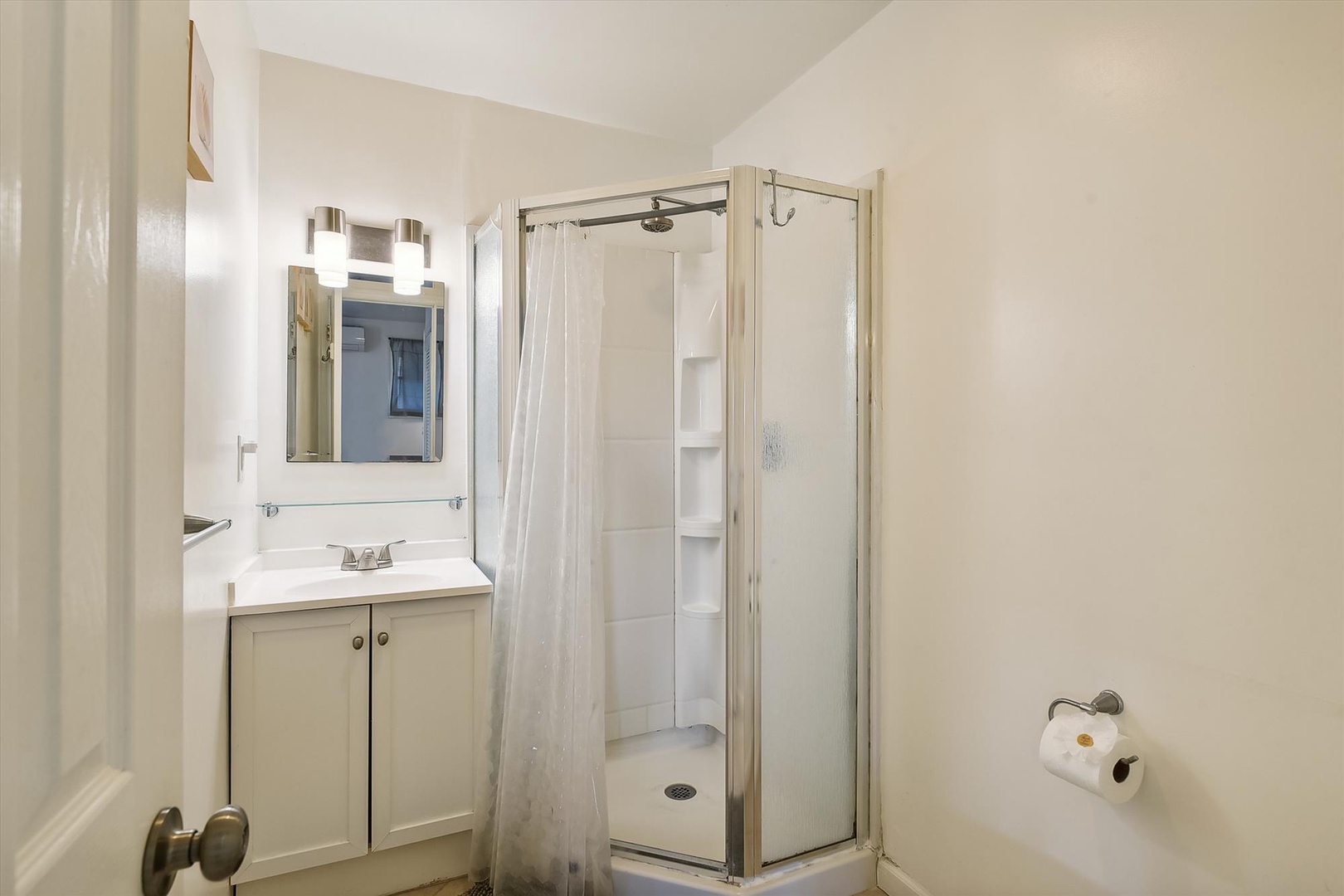 Your private bathroom features a clean, modern shower and vanity with plenty of lighting. Fresh, crisp, and ready for your stay—everything you need to feel right at home.