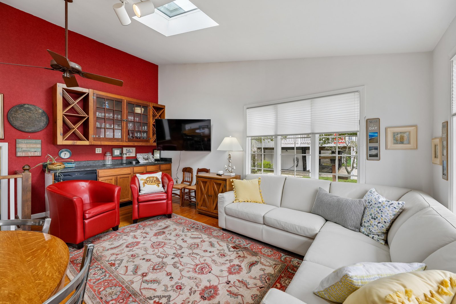 Settle into this bright, welcoming living room where vibrant red accents and custom cabinetry create a warm home-away-from-home feel. Soft natural light floods through the skylight and windows, perfect for your downtime.