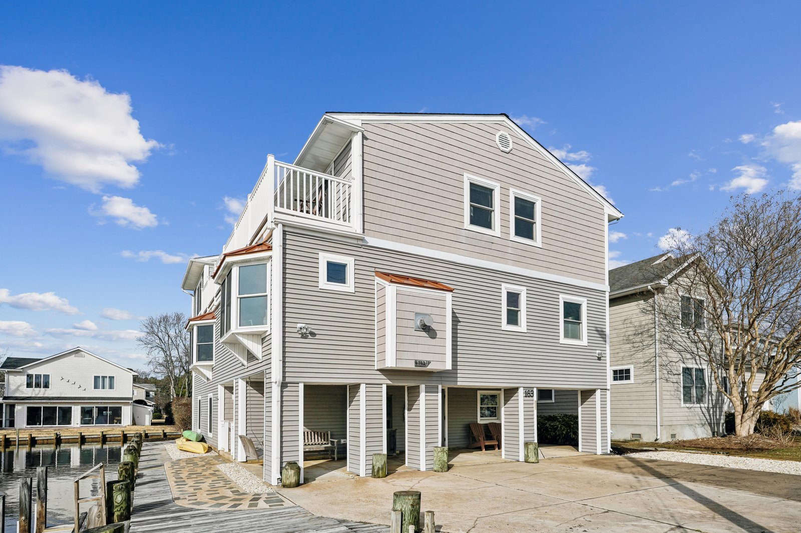 Waterfront retreat with private dock access and elevated balconies overlooking the neighborhood canal. Coastal architecture offers convenient ground-level parking and multiple outdoor spaces.