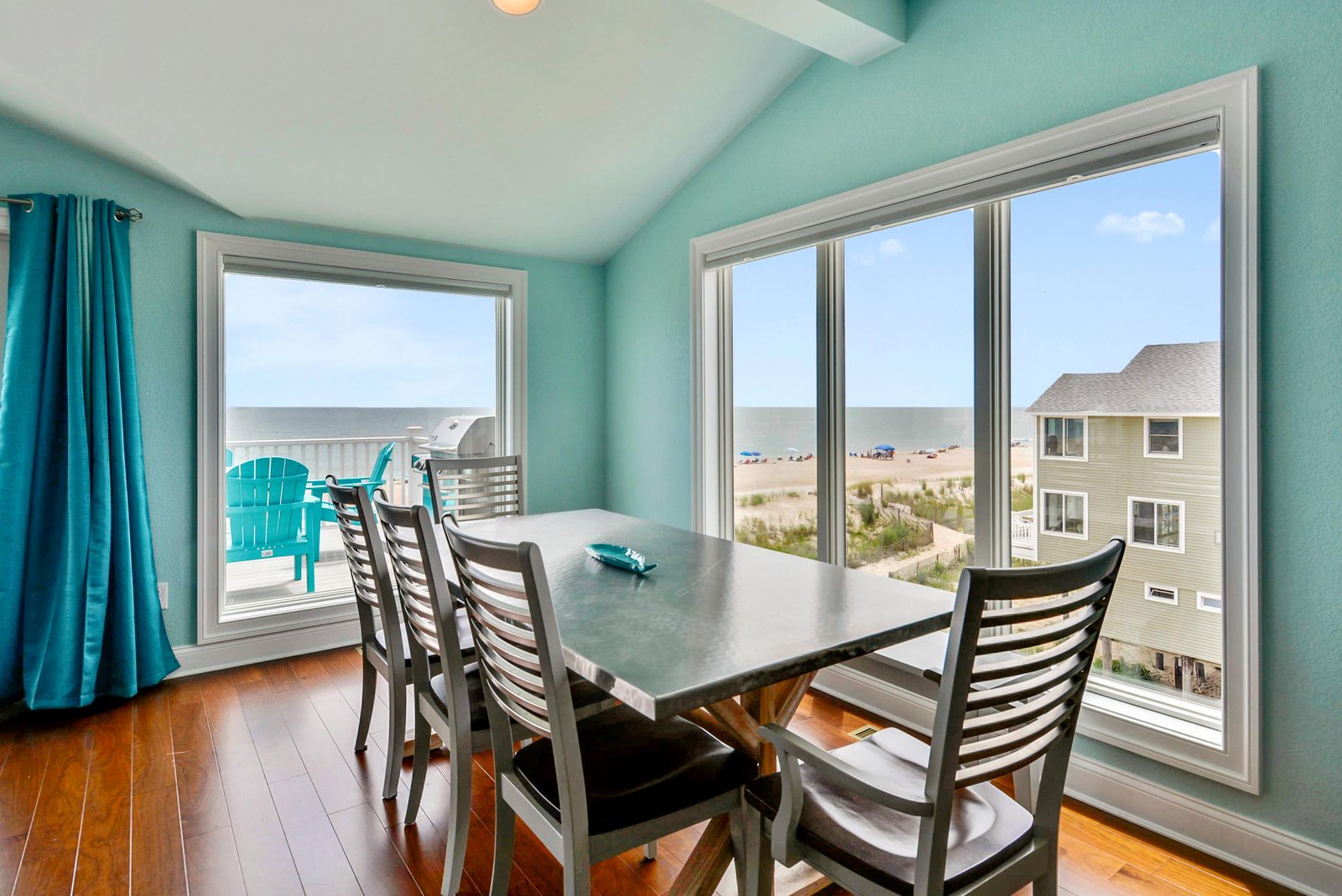 Savor morning coffee at this dining table with golden sand and sparkling ocean views. Bright turquoise accents echo the sea beyond, while the private balcony invites you to enjoy the coastal breeze.