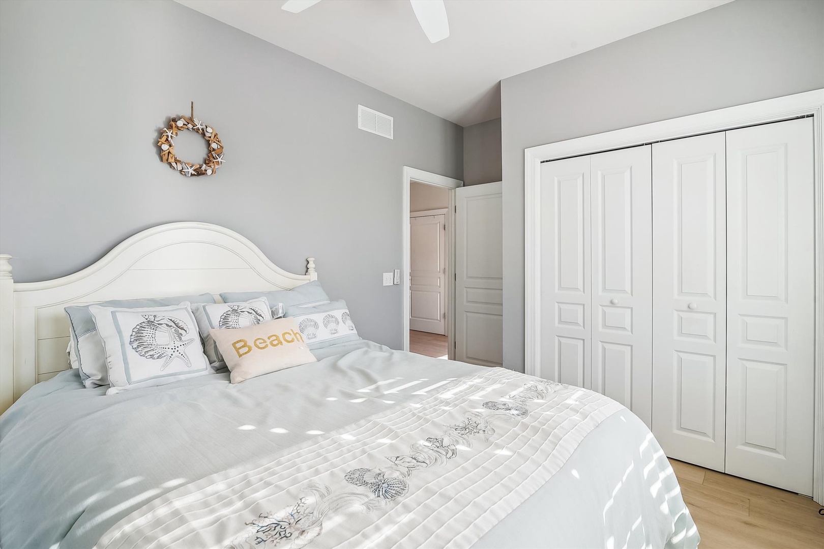 Drift off to sleep in this serene coastal bedroom with soft grey walls, plush bedding adorned with sea-inspired accents, and ample storage for your belongings. You'll love the peaceful beach vibes.