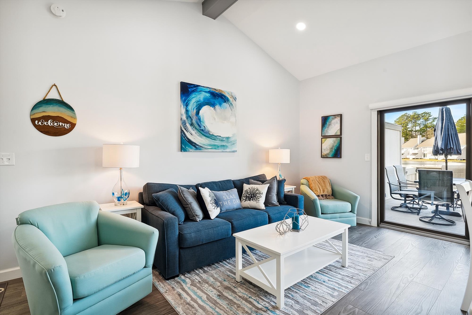 Unwind in your coastal-themed living room featuring a plush sofa, bright turquoise chairs, and stylish ocean art creating the perfect seaside retreat atmosphere.