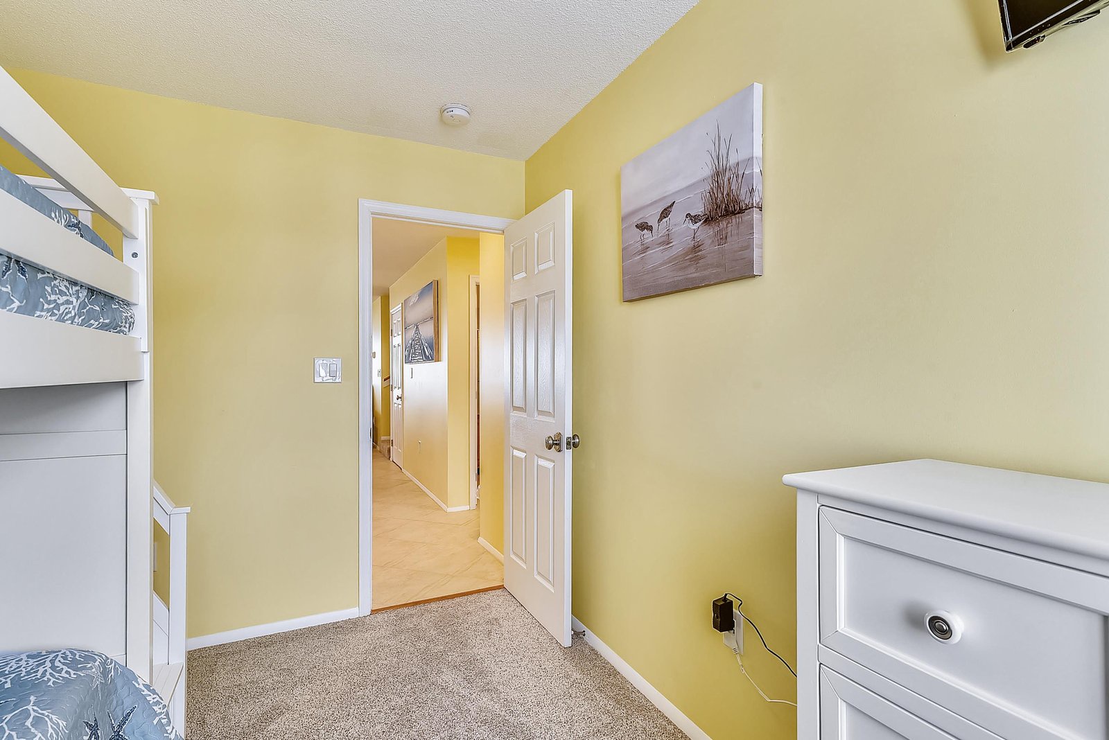 Your cheerful yellow bedroom features a cozy bunk bed and white dresser, perfect for the kids' comfort and a peaceful night's rest.
