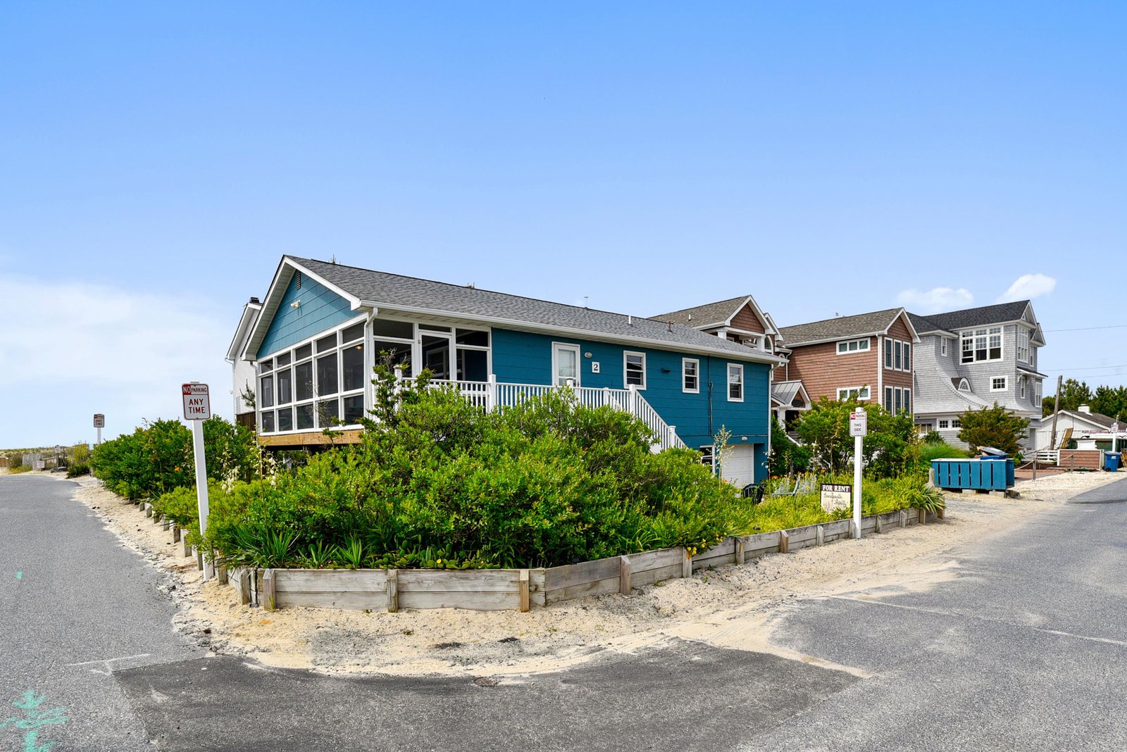 This cheerful beach house sits just steps from the shore, surrounded by coastal greenery. Its welcoming blue exterior and beachside location set the stage for relaxing coastal getaways.