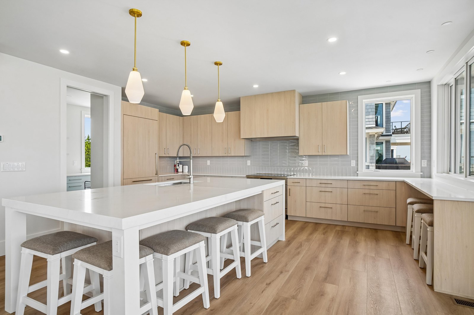 Step into this bright, modern kitchen with warm wood cabinetry and a spacious island where you can gather for meals or prep your favorite dishes. Natural light pours in, creating an inviting space for cooking and conversation.