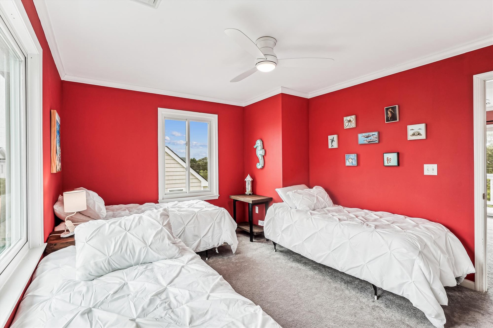 Cozy up in your bright, cheerful bedroom featuring plush beds and playful coastal decor. A ceiling fan keeps you comfortable while charming wall art adds character to your restful retreat.