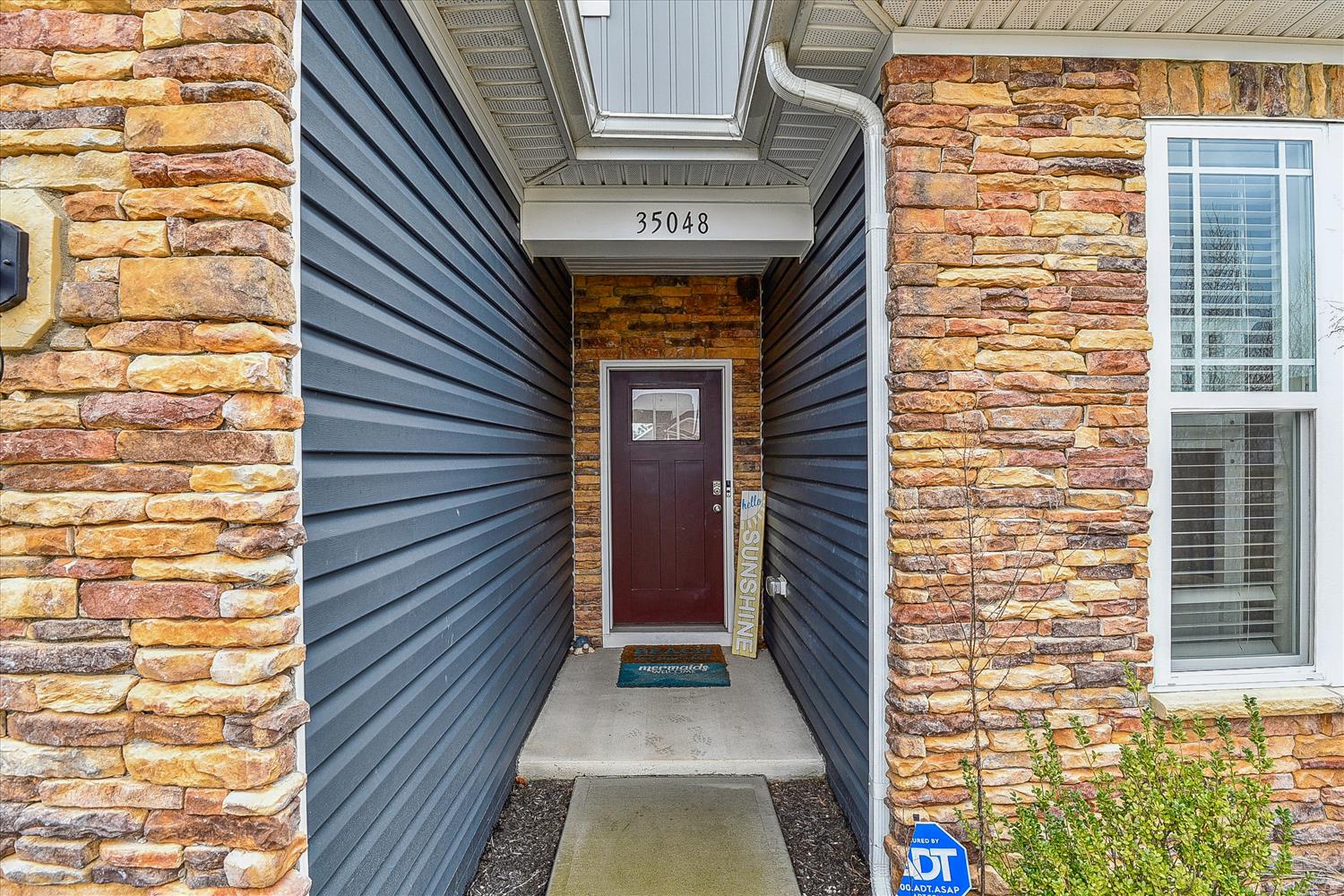 The property entrance at 35048 features contemporary dark blue horizontal siding complemented by warm, multicolored stone accents that create visual interest and curb appeal.