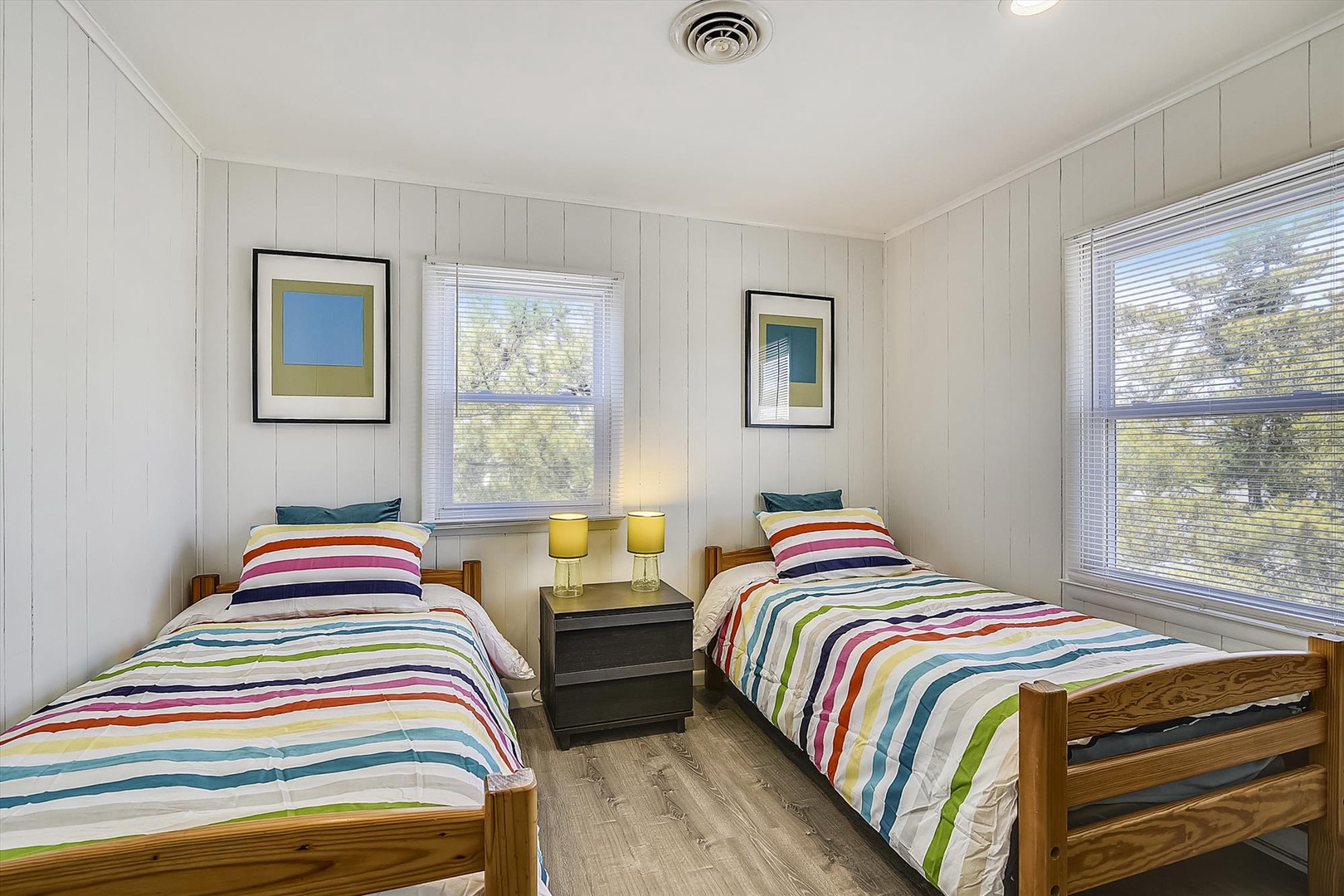 Bright twin bedroom with cheerful striped bedding, natural light, and cozy touches—perfect for your group or family stay.