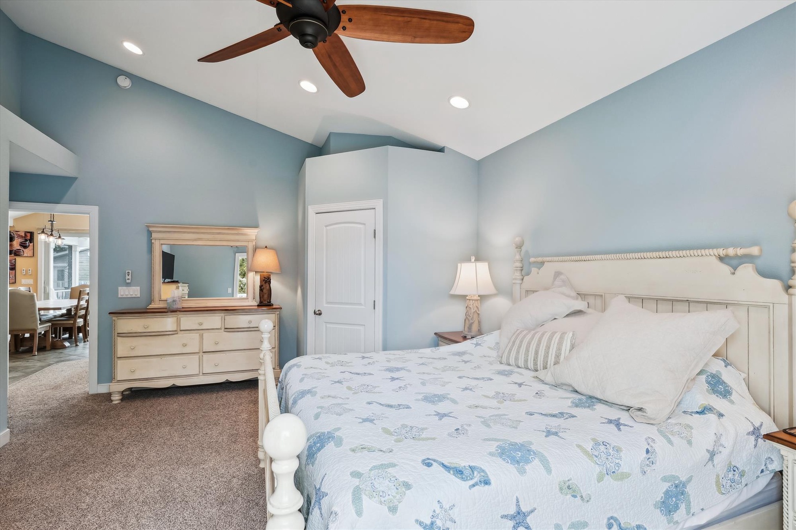 Your coastal-inspired bedroom awaits with soft blue tones, plush bedding featuring ocean motifs, and a ceiling fan to keep you comfortable. Settle in and drift off to the gentle rhythm of your vacation retreat.