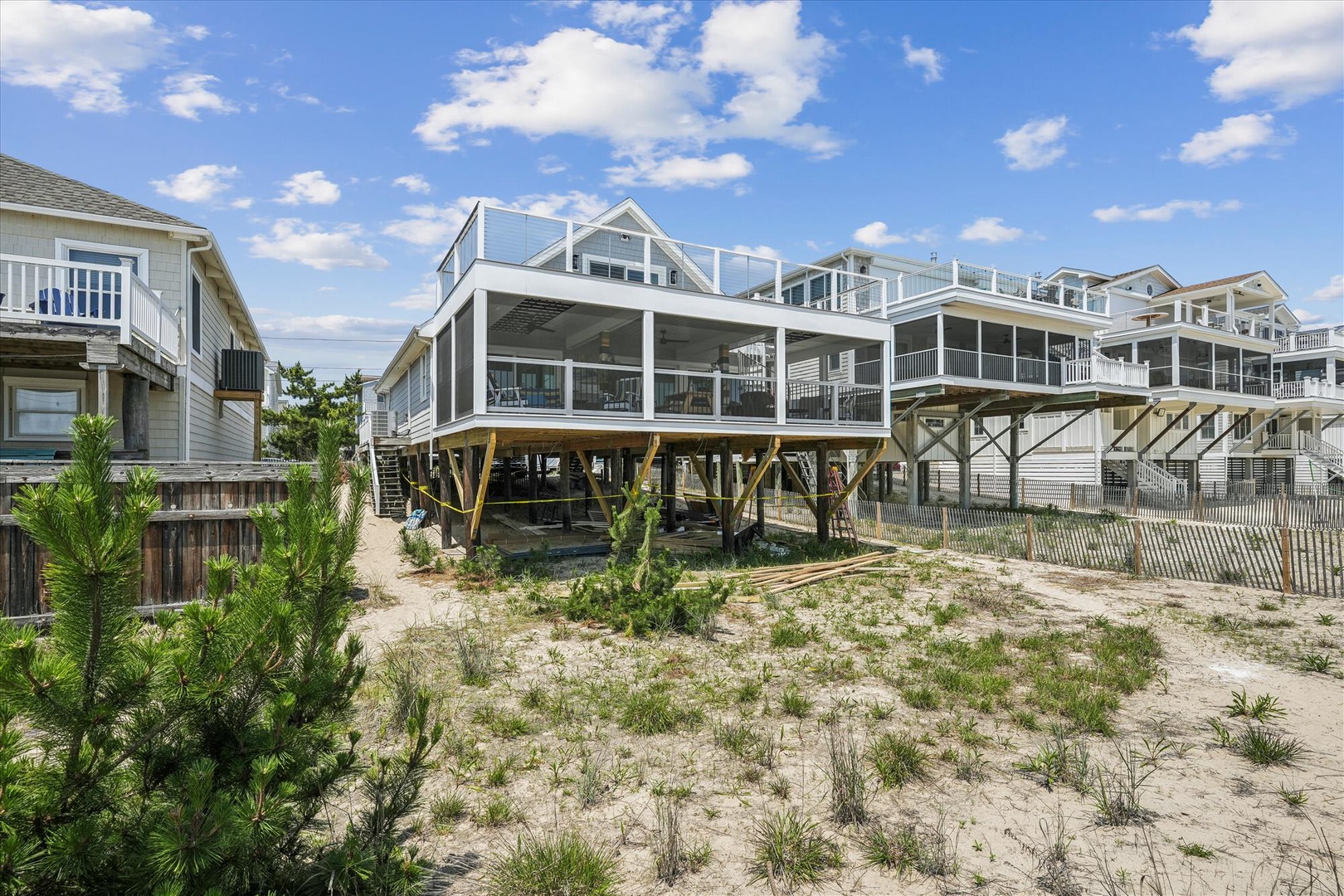 Modern beachfront property elevated on sturdy pilings, situated directly on sandy shores with neighboring coastal homes. A prime oceanside location offering immediate beach access.