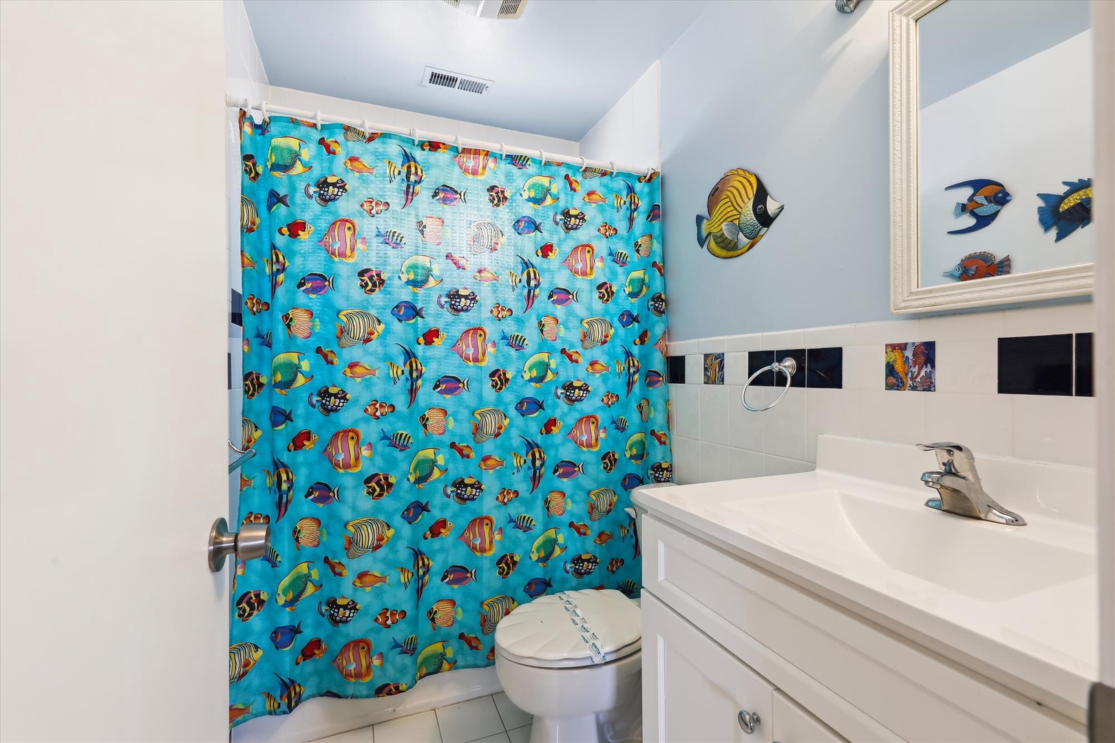 Dive into your own underwater adventure in this kid-friendly bathroom, complete with playful tropical fish décor and a whimsical ocean-themed shower curtain.