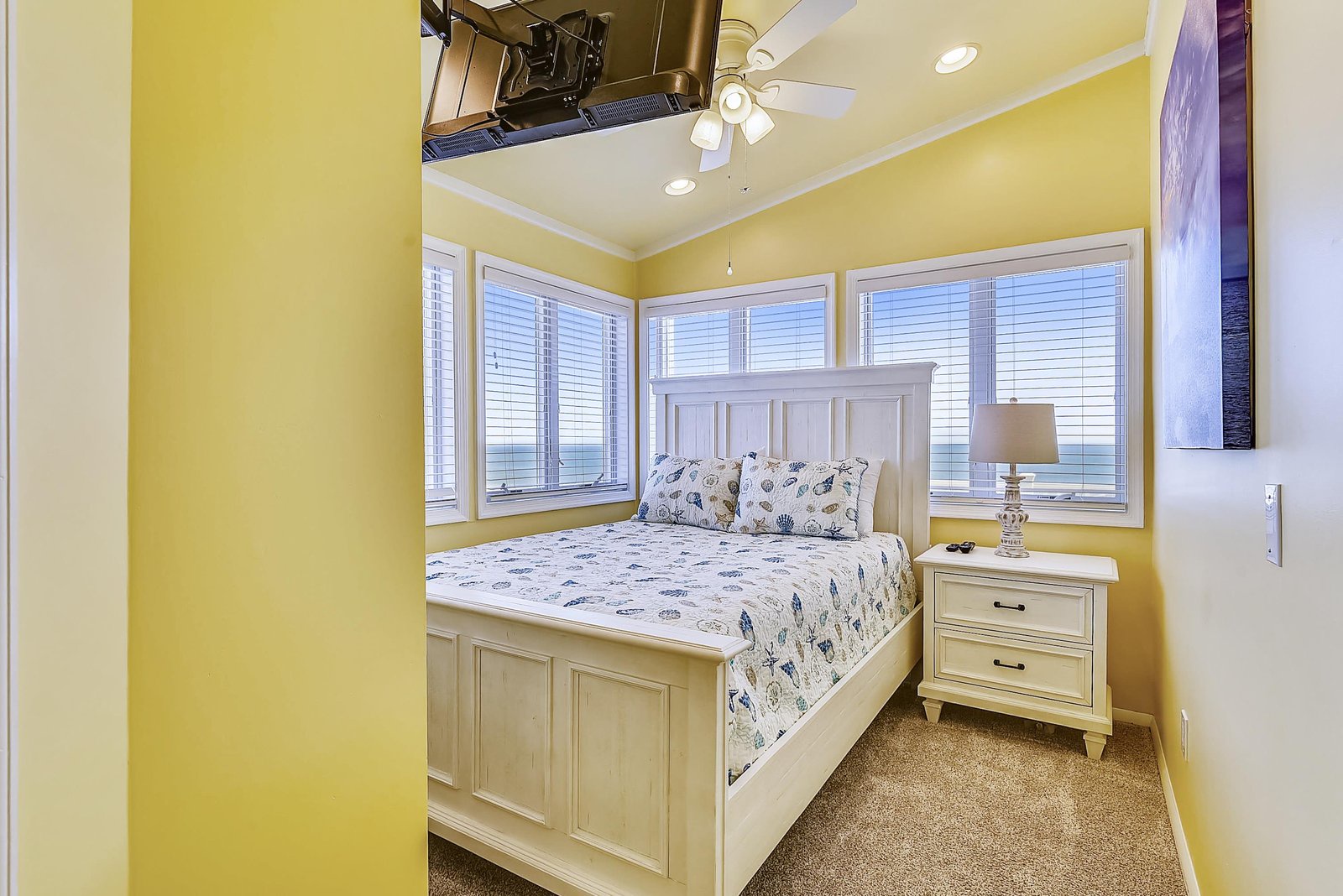 Wake up to stunning ocean views through bright windows that frame the sea beyond. Cheerful yellow walls and coastal-themed bedding create a sunny, restful retreat for your beach getaway.