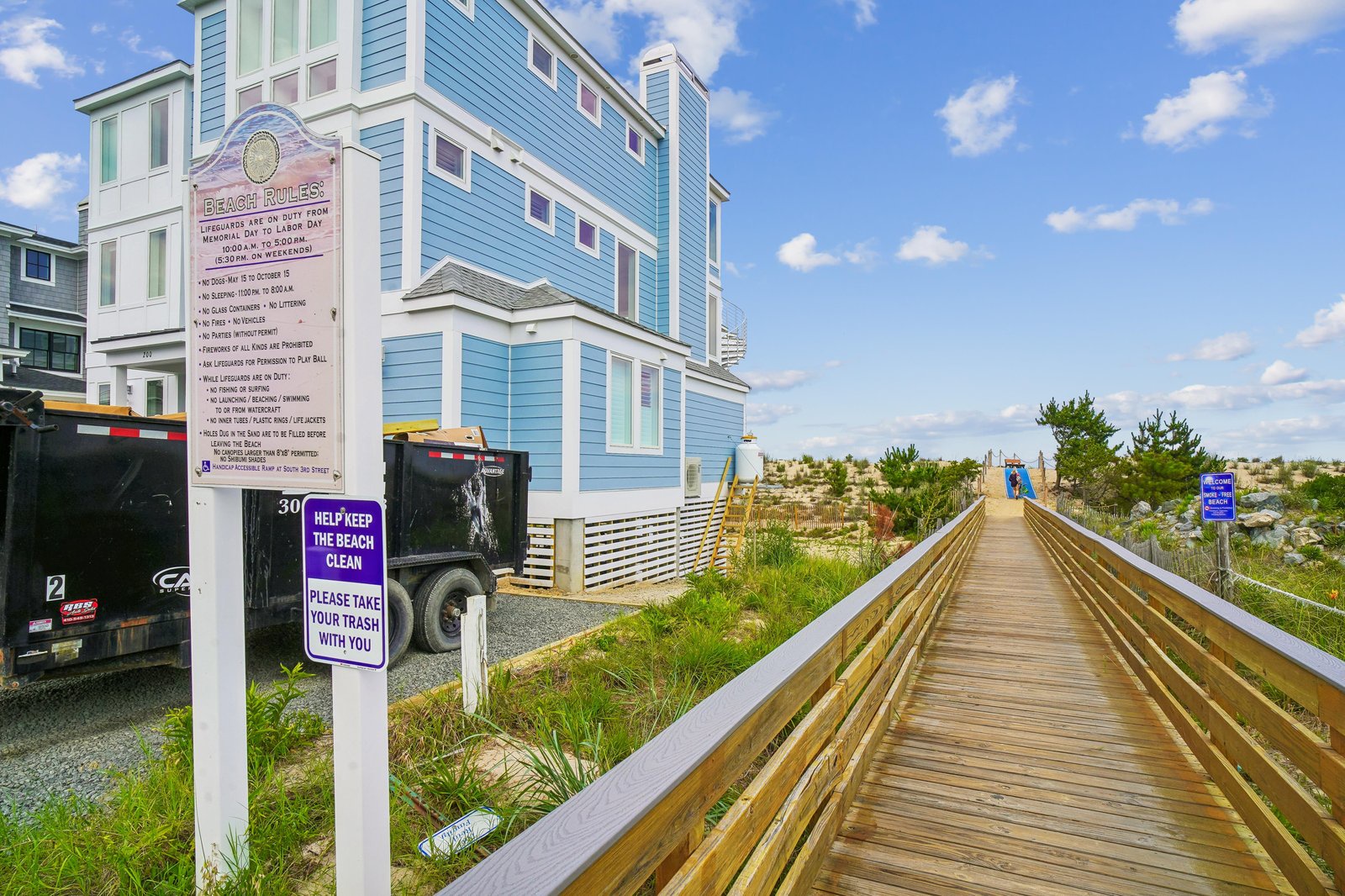 A charming beachfront property featuring a convenient boardwalk that leads directly to the sandy shore, surrounded by coastal dunes and natural beach grasses.