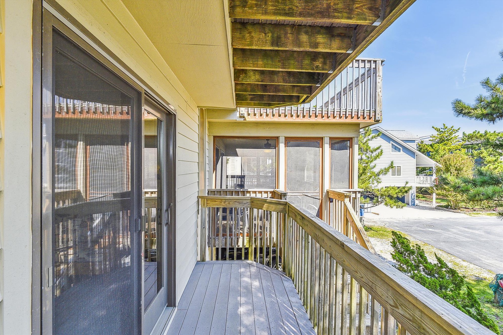 A private balcony wraps around bright living space, letting you soak up coastal sunshine and breezy neighborhood views. Wooden railings frame peaceful moments outdoors—perfect for morning coffee or winding down after a beach day.
