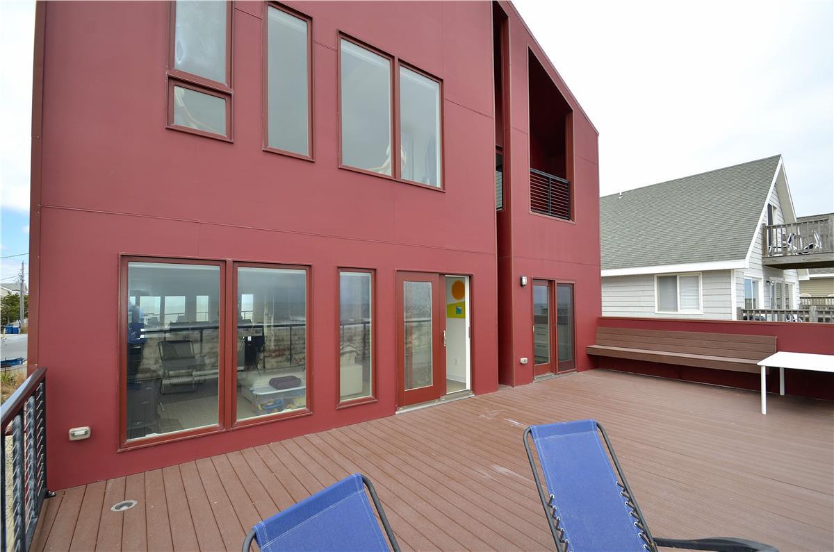 Contemporary waterfront property featuring a spacious deck with direct access to the water. The distinctive red architecture provides a striking backdrop for your coastal getaway.