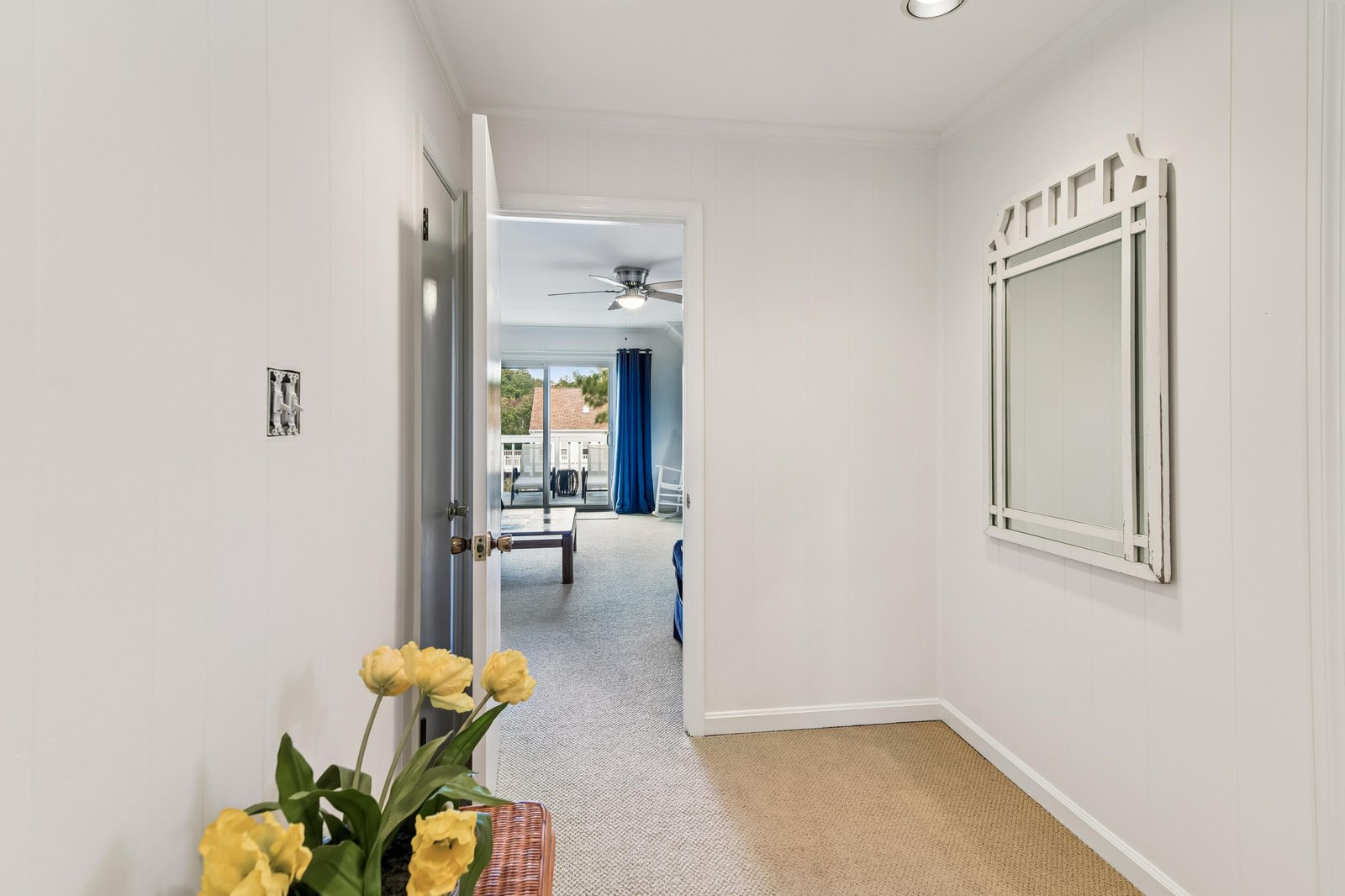 A bright, welcoming hallway leads you into your vacation space, with cheerful yellow blooms and a glimpse of the cozy living area beyond.