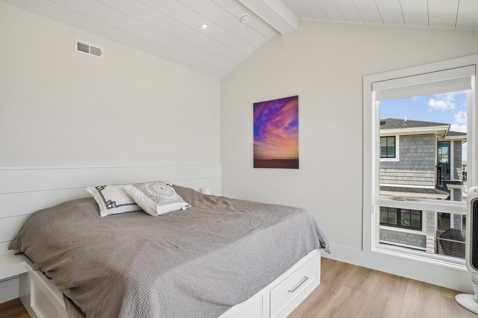 Drift off in this serene bedroom, where soft textures meet coastal charm. The subtle shiplap accent and vaulted ceiling create a sense of calm, while your window frames a peaceful neighborhood view.