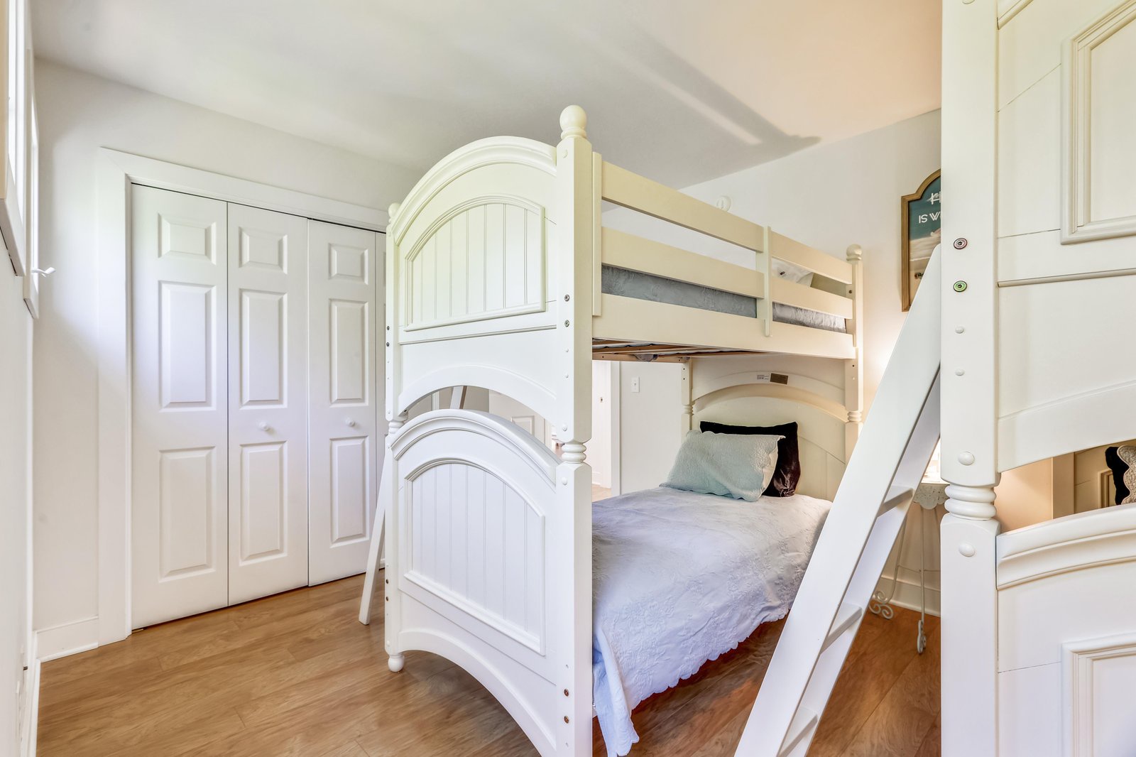 Your kids will love this cozy bunk room, with its charming white furniture and warm wood floors creating a playful, restful space that feels just like home.