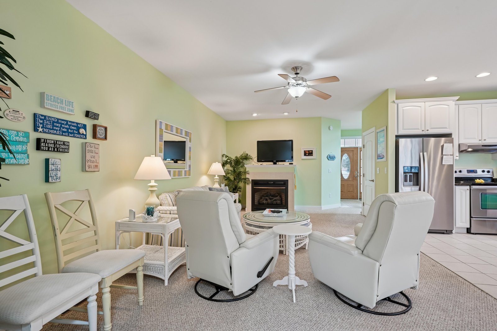 Relax in your bright, beach-themed living space with comfy seating, a cozy fireplace, and an open kitchen—perfect for unwinding after a day of exploring.