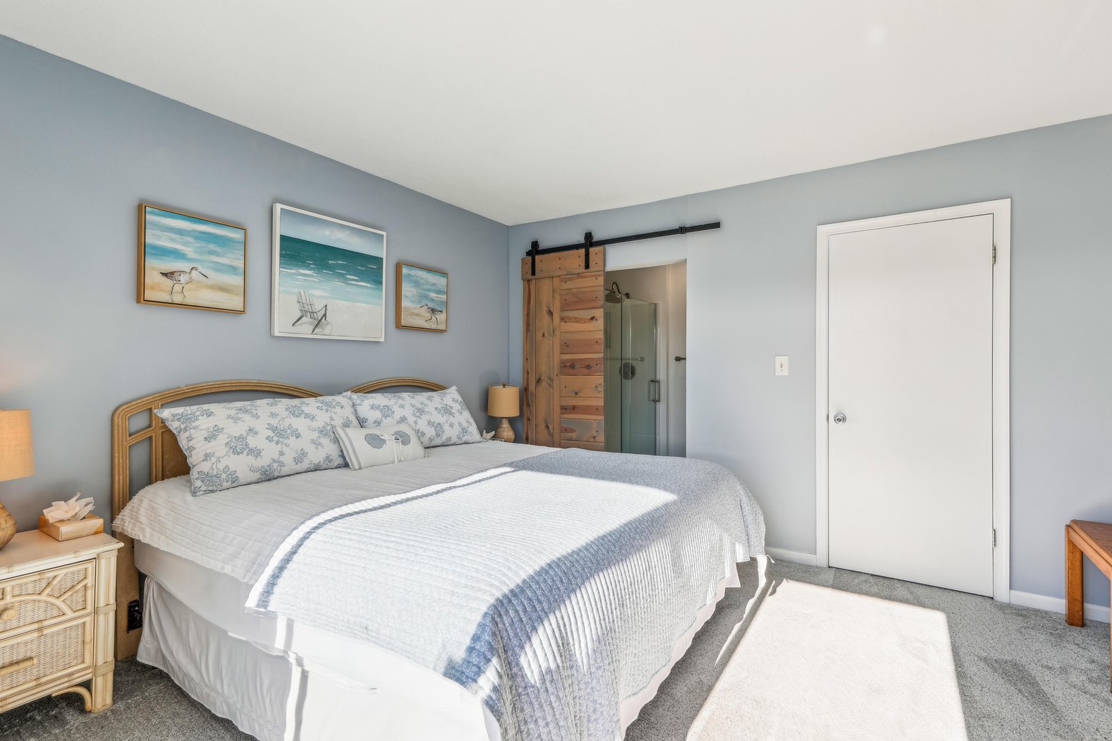 Your peaceful coastal-inspired bedroom features soothing blue tones and charming rustic barn door details that invite you to unwind in style.
